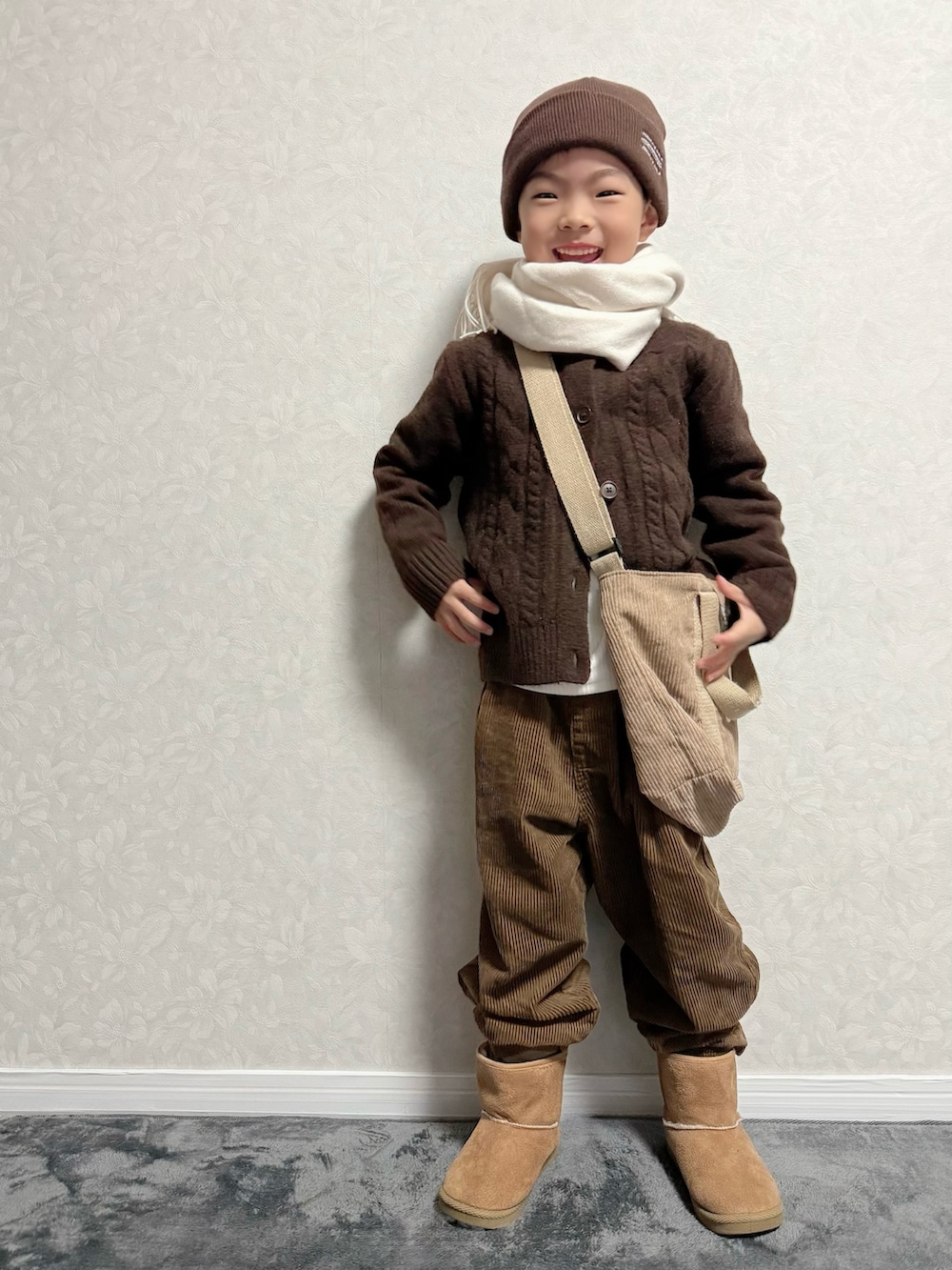 ブラウン系のカーディガン/ボレロ、ホワイト系のTシャツ/カットソー、ブラウン系のパンツを着用したキッズの冬コーディネートの2枚目の写真