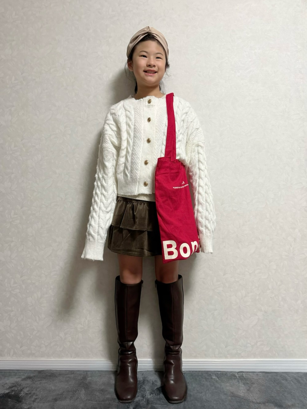 ホワイト系のカーディガン/ボレロ、ベージュ系のTシャツ/カットソー、ブラウン系のブーツを着用したキッズの秋コーディネートの2枚目の写真