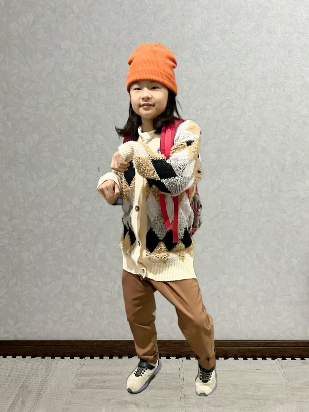 ホワイト系のTシャツ/カットソー、ベージュ系のカーディガン/ボレロ、レッド系のバックパック/リュックを着用したキッズの冬コーディネートの2枚目の写真