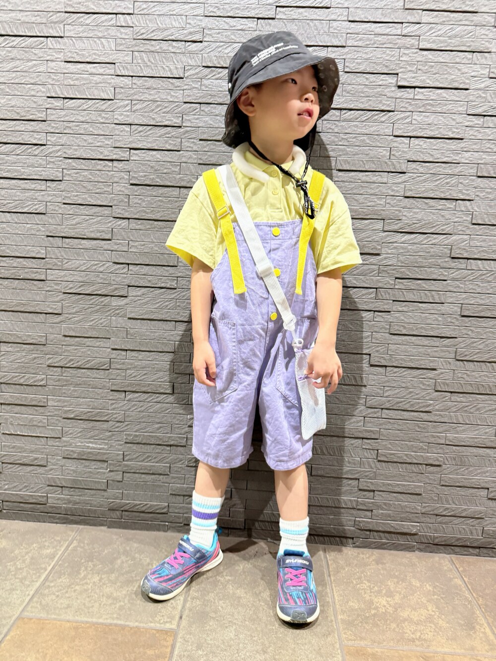 ブルー系のスニーカー、イエロー系のポロシャツ、パープル系のサロペット/オーバーオールを着用したキッズの秋コーディネートの5枚目の写真