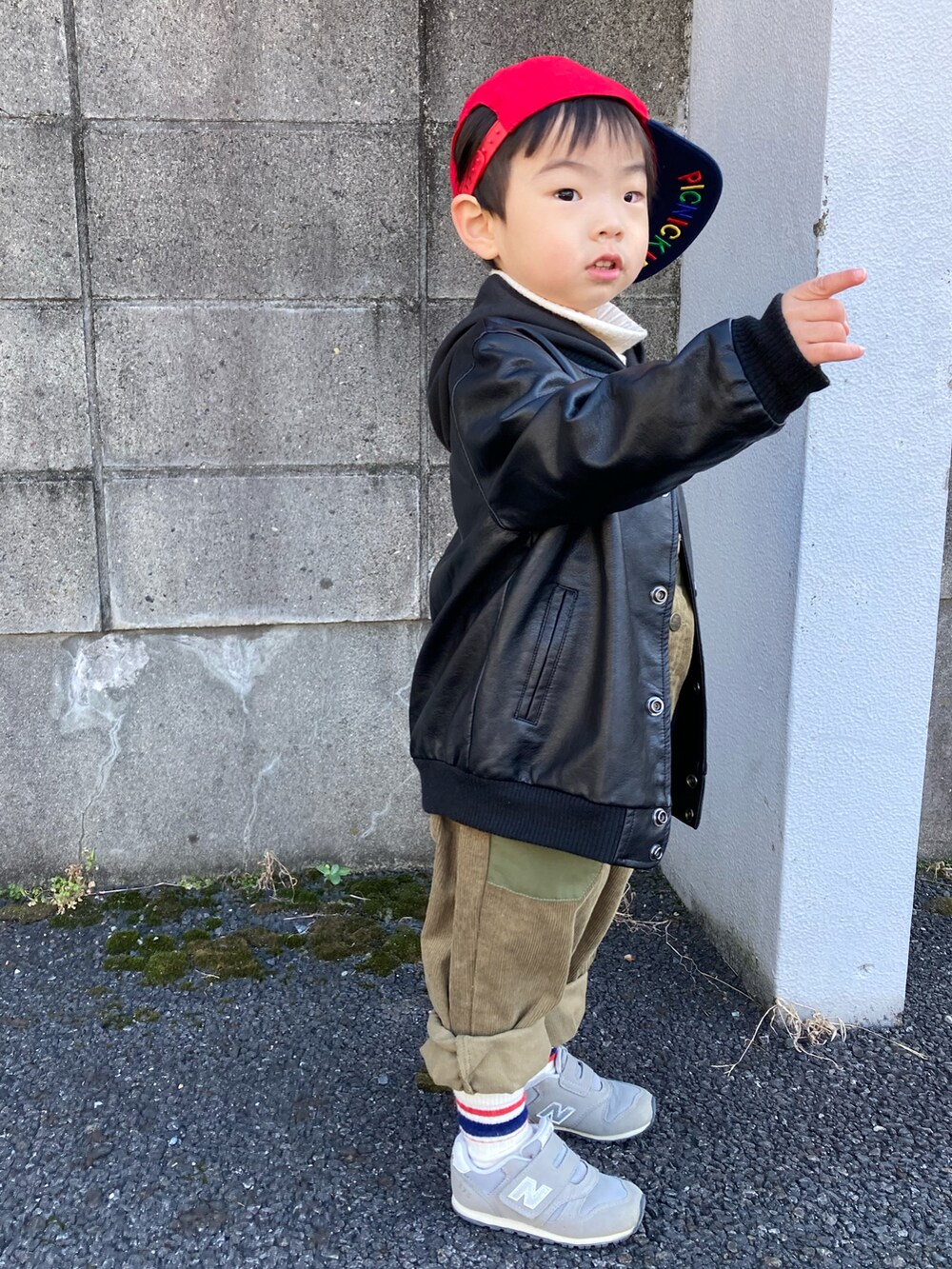 ブラック系のパーカー、グリーン系のサロペット/オーバーオール、グレー系のスニーカーを着用したキッズの冬コーディネートの2枚目の写真