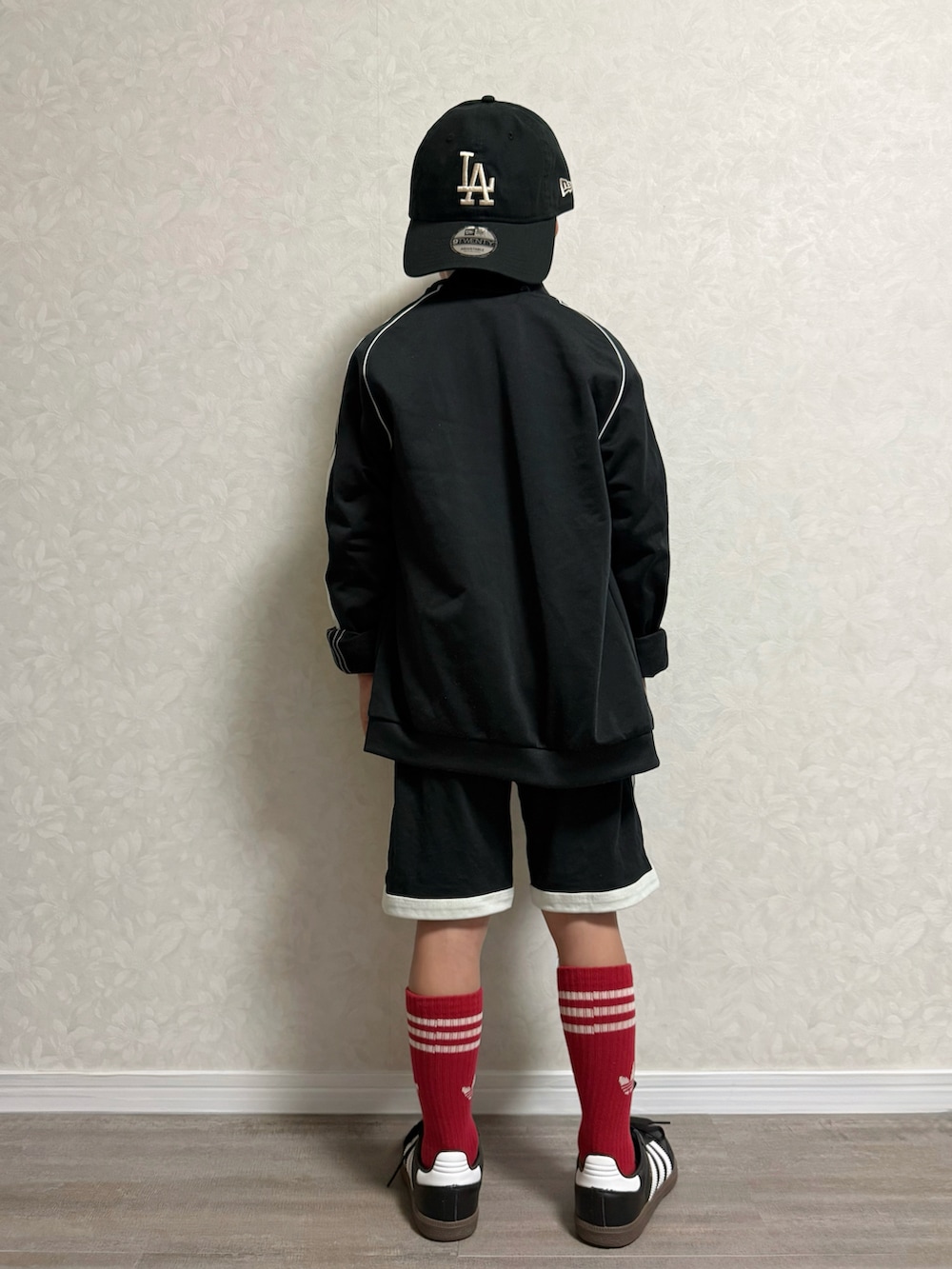 ブラック系のセットアップ、ブラック系のスニーカー、ホワイト系のTシャツ/カットソーを着用したキッズの秋コーディネートの5枚目の写真