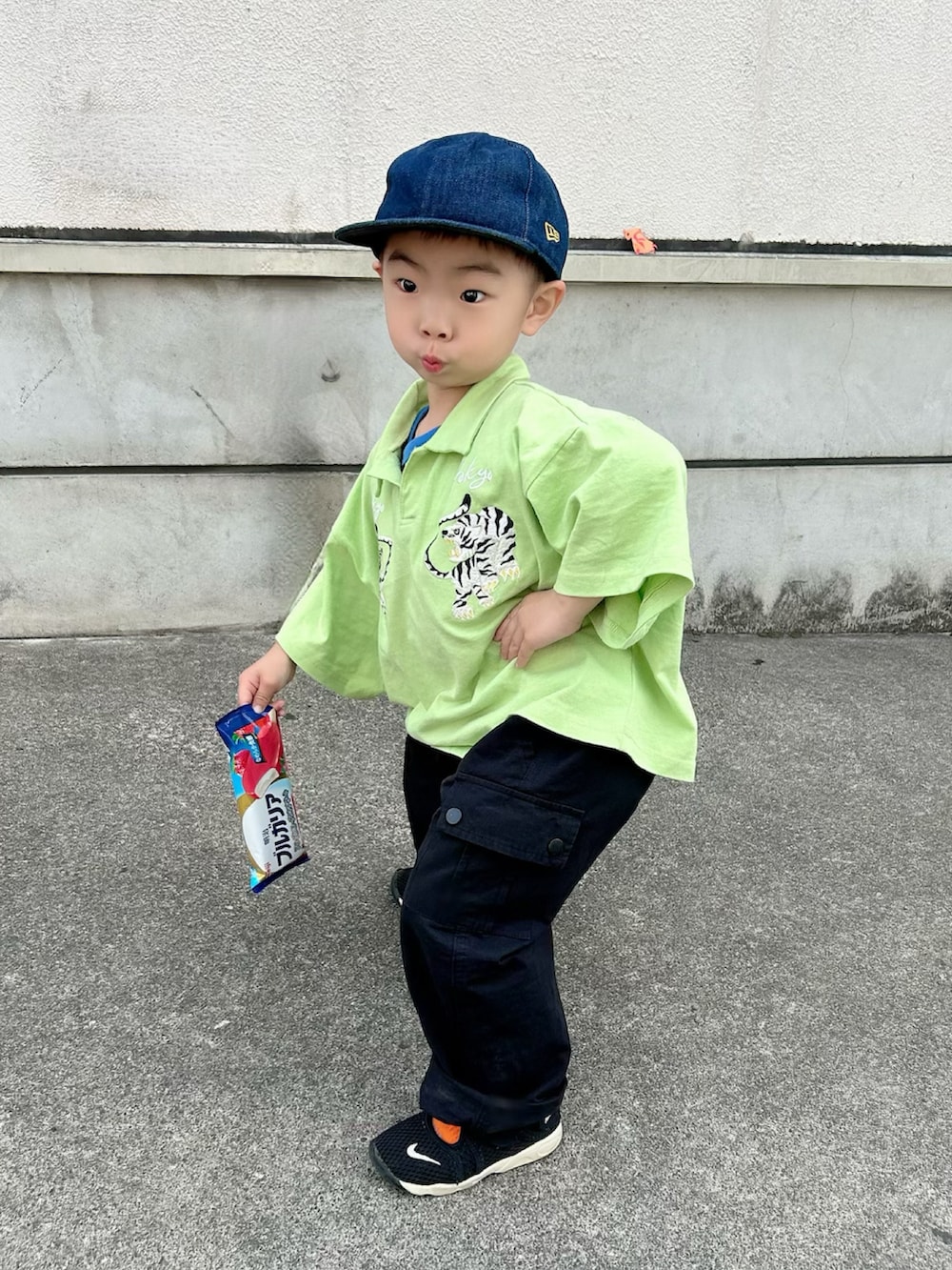 ブラック系のタンクトップ、グリーン系のポロシャツ、ブラック系のカーゴパンツを着用したキッズの春コーディネートの3枚目の写真