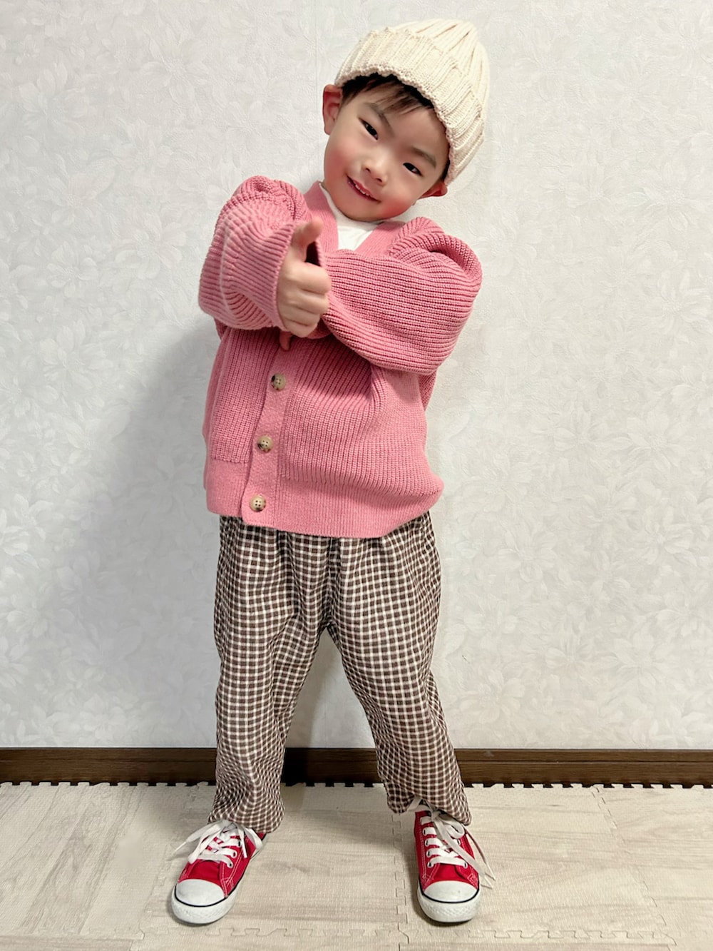 ホワイト系のニット/セーター、ピンク系のカーディガン/ボレロ、ブラウン系のパンツを着用したキッズの冬コーディネートの3枚目の写真