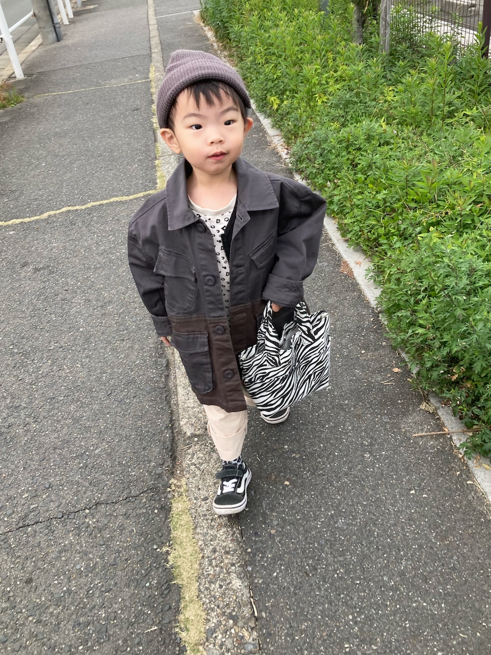 ベージュ系のTシャツ/カットソー、ブラック系のベスト、ベージュ系のチノパンツを着用したキッズの秋コーディネートの4枚目の写真