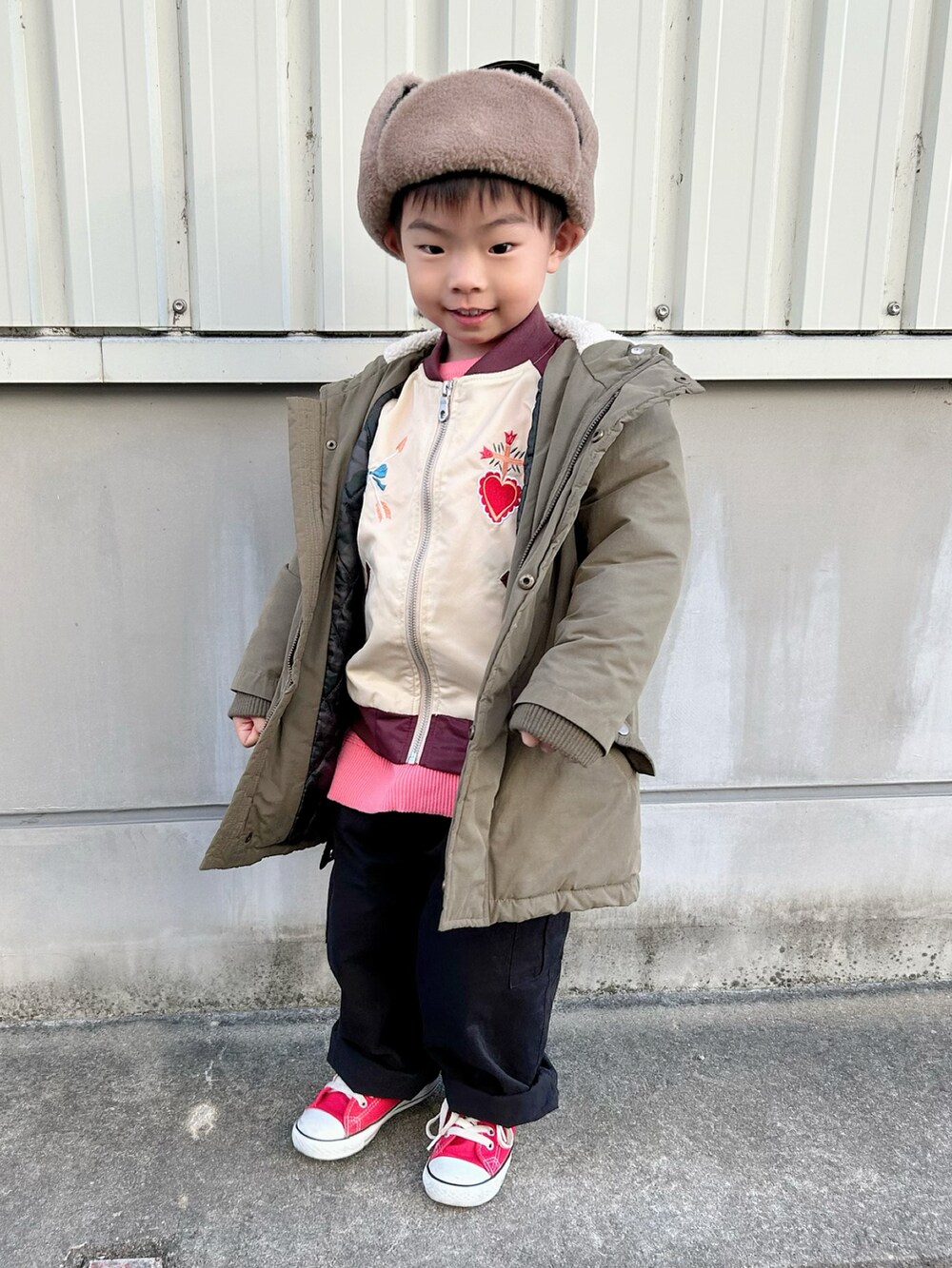 ピンク系のニット/セーター、レッド系のブルゾン、グリーン系のモッズコートを着用したキッズの冬コーディネートの3枚目の写真