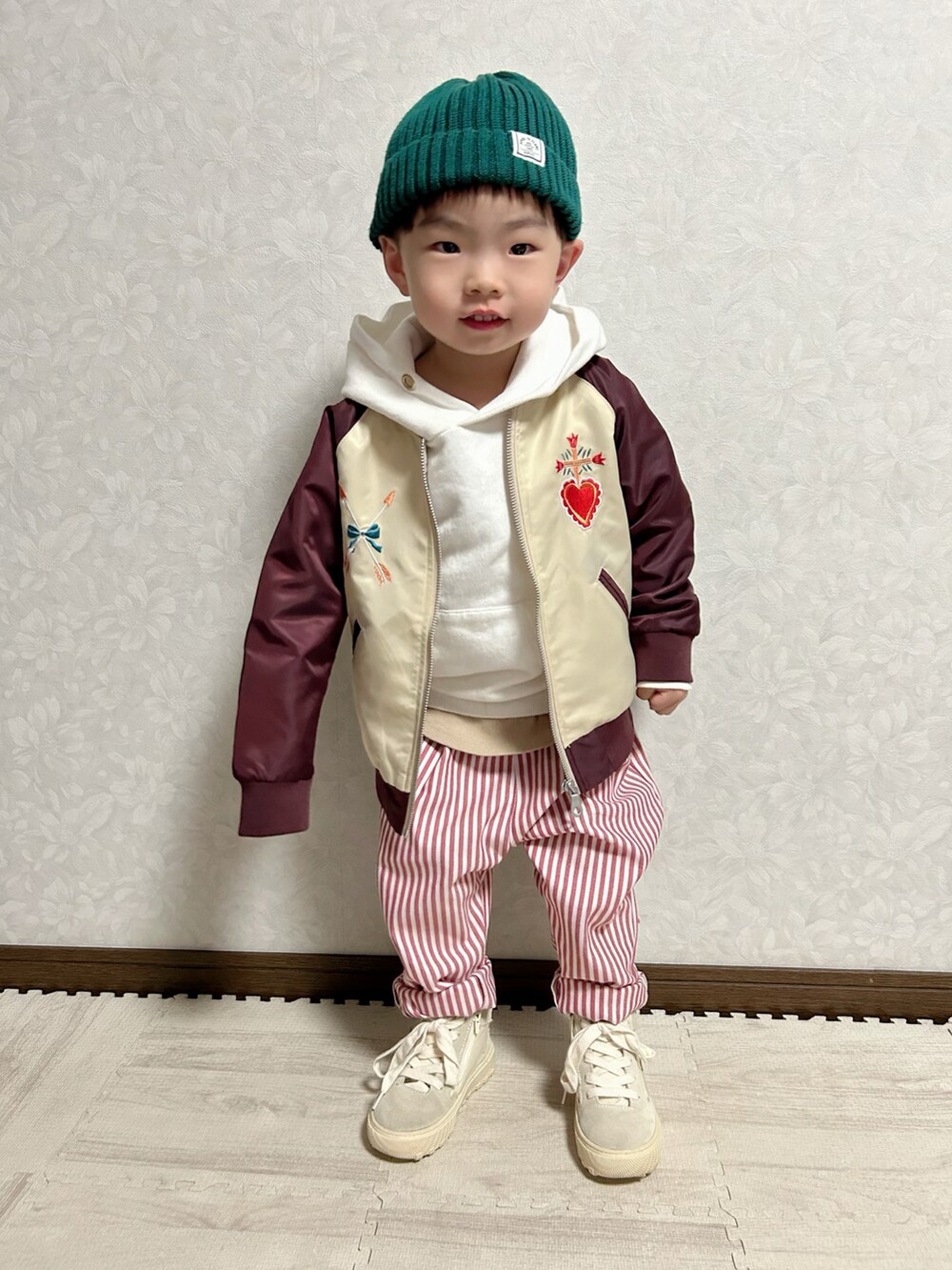 レッド系のブルゾン、ベージュ系のタンクトップ、ホワイト系のパーカーを着用したキッズの春コーディネートの2枚目の写真