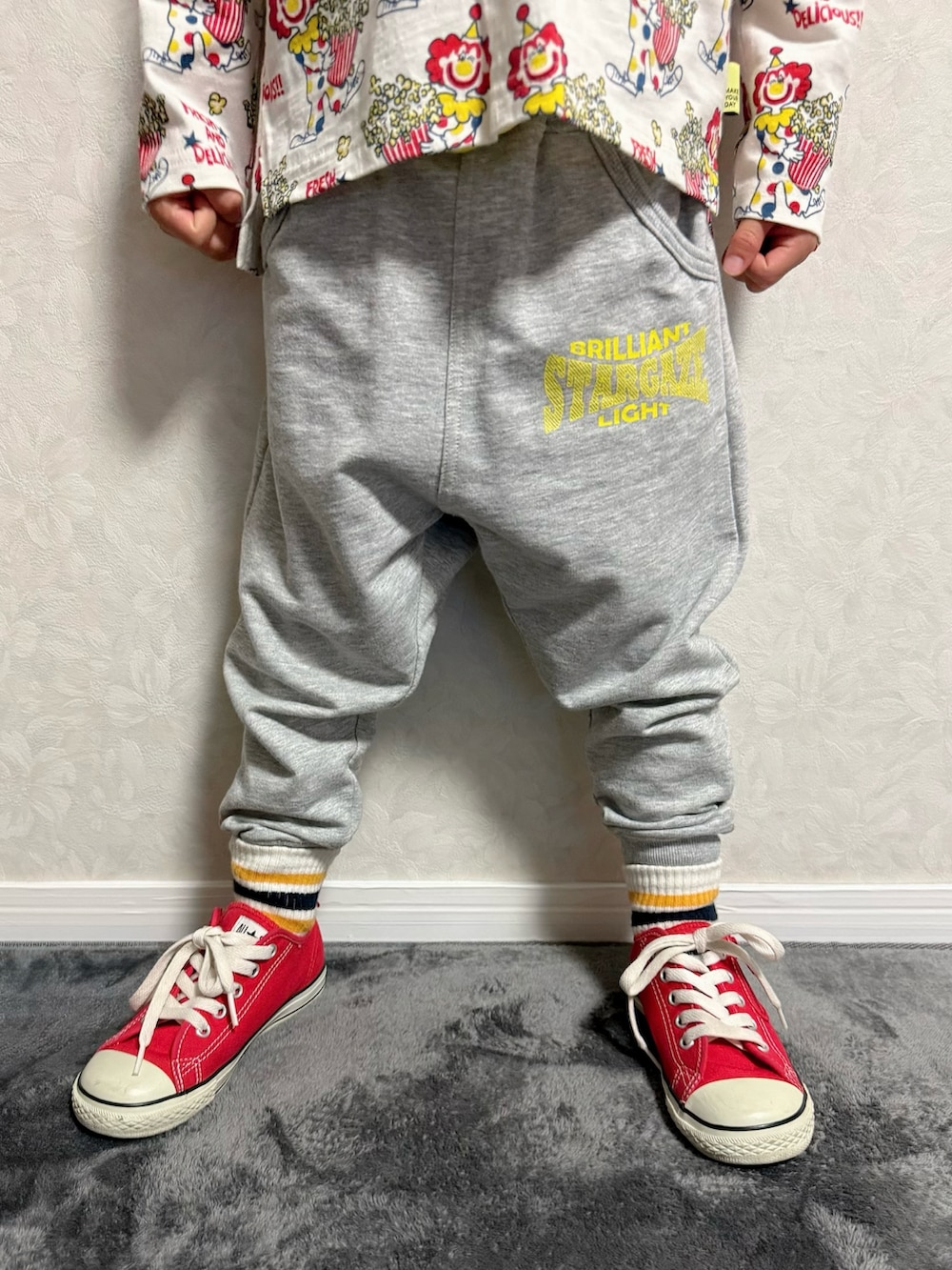 レッド系のスニーカー、ベージュ系のTシャツ/カットソー、グレー系のスウェットパンツを着用したキッズの冬コーディネートの3枚目の写真