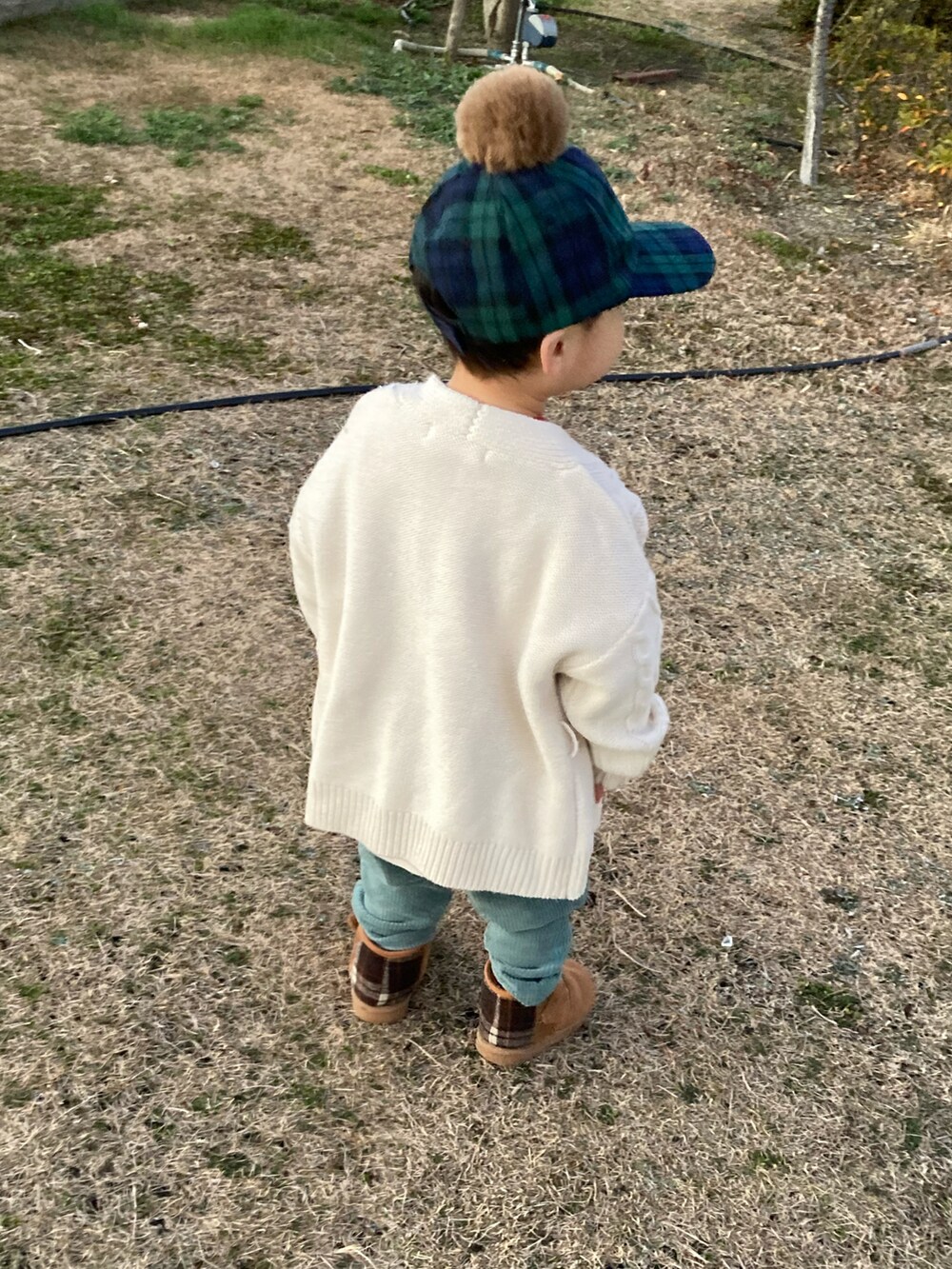 レッド系のスウェット、ホワイト系のカーディガン/ボレロ、グリーン系のその他パンツを着用したキッズの冬コーディネートの2枚目の写真