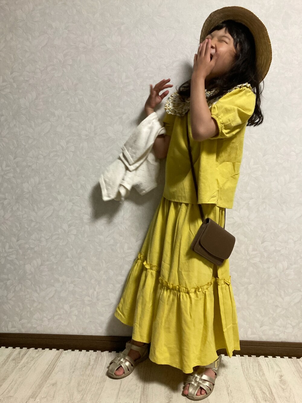 イエロー系のセットアップ、ホワイト系のカーディガン/ボレロ、ブラウン系のショルダーバッグを着用したキッズの春コーディネートの4枚目の写真