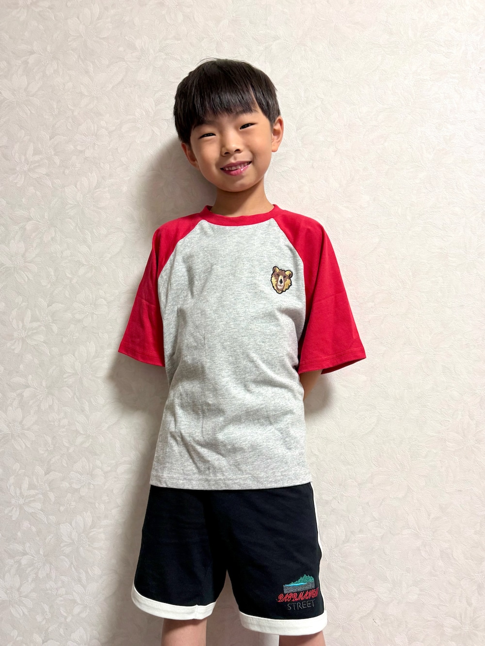 レッド系のTシャツ/カットソー、ブラック系のショルダーバッグ、ブラック系のセットアップを着用したキッズの夏コーディネートの3枚目の写真