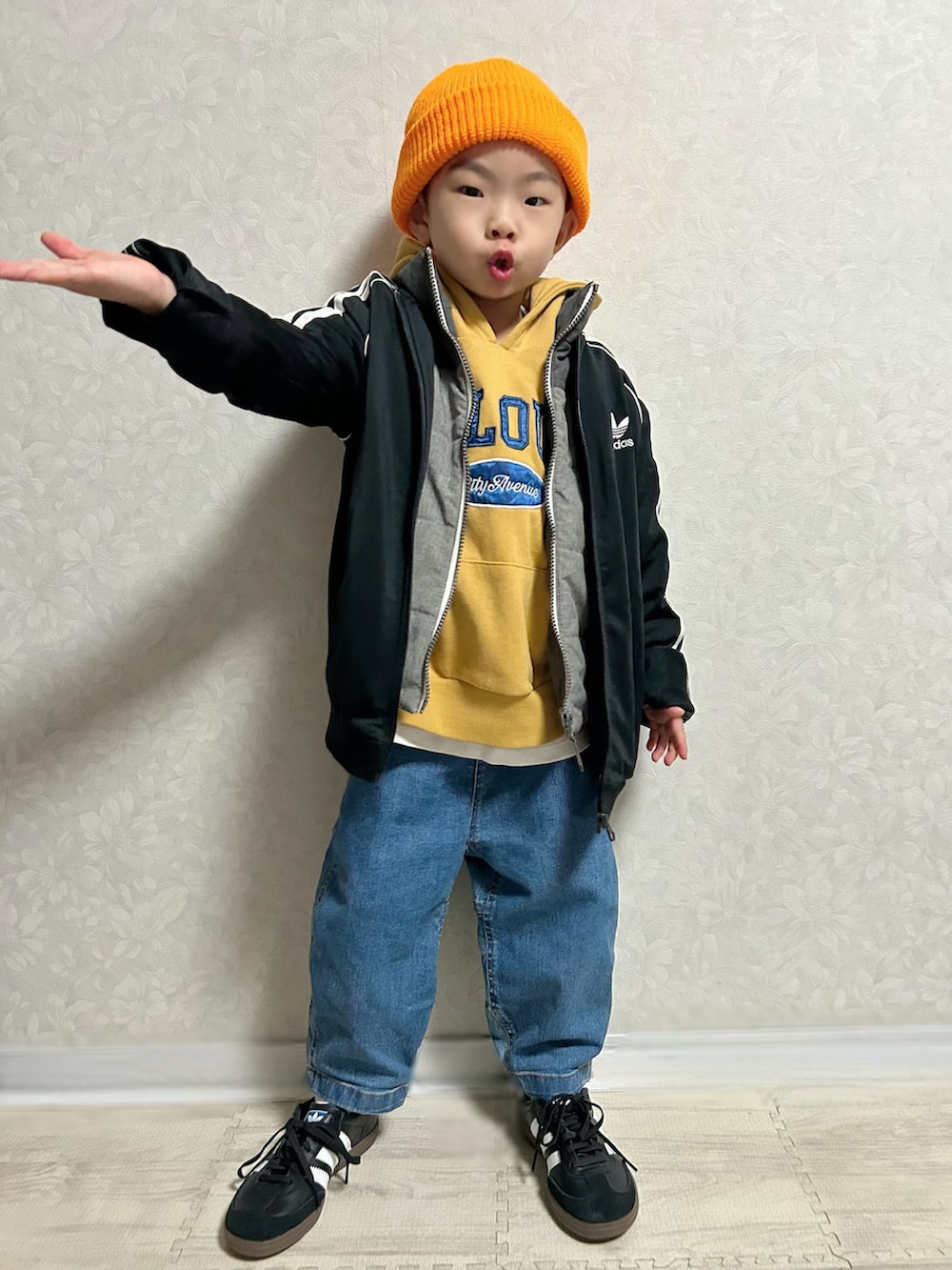 イエロー系のパーカー、グレー系のダウンベスト、ブラック系のジャージを着用したキッズの冬コーディネートの3枚目の写真