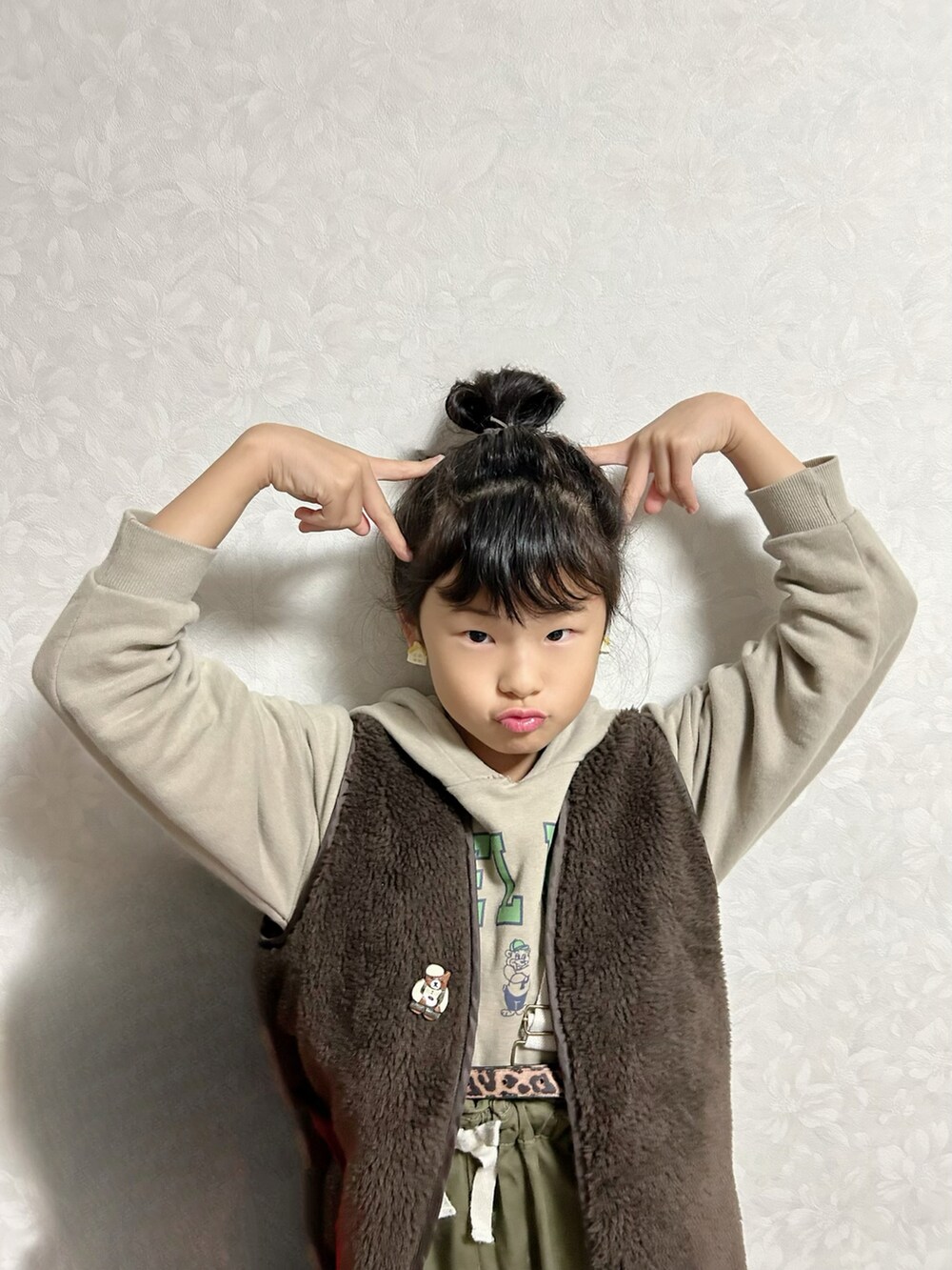 ベージュ系のパーカー、グリーン系のスウェット、グリーン系のサロペット/オーバーオールを着用したキッズの冬コーディネートの4枚目の写真