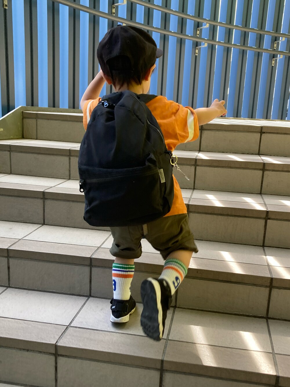 オレンジ系のTシャツ/カットソー、グリーン系のカーゴパンツ、ブラック系のスニーカーを着用したキッズの夏コーディネートの4枚目の写真