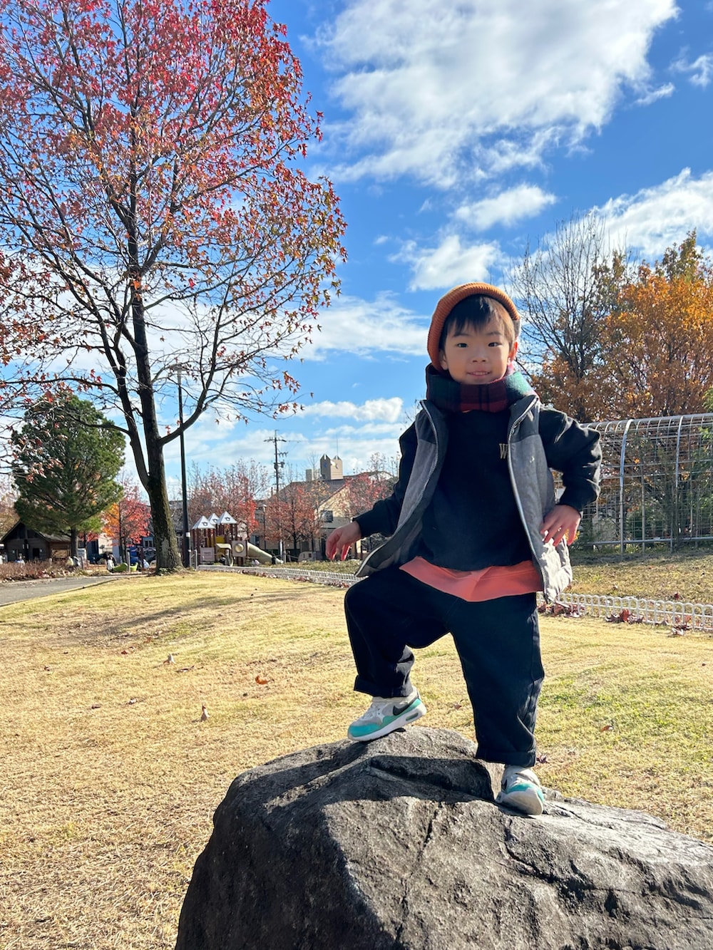 オレンジ系のスウェット、グレー系のスウェット、グレー系のダウンベストを着用したキッズの冬コーディネートの4枚目の写真