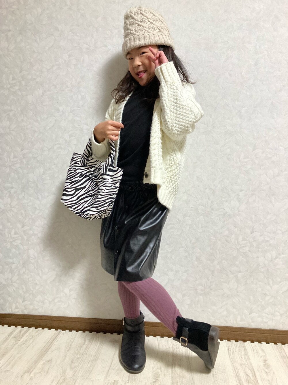 ブラック系のニット/セーター、ホワイト系のカーディガン/ボレロ、ブラック系のスカートを着用したキッズの冬コーディネートの4枚目の写真