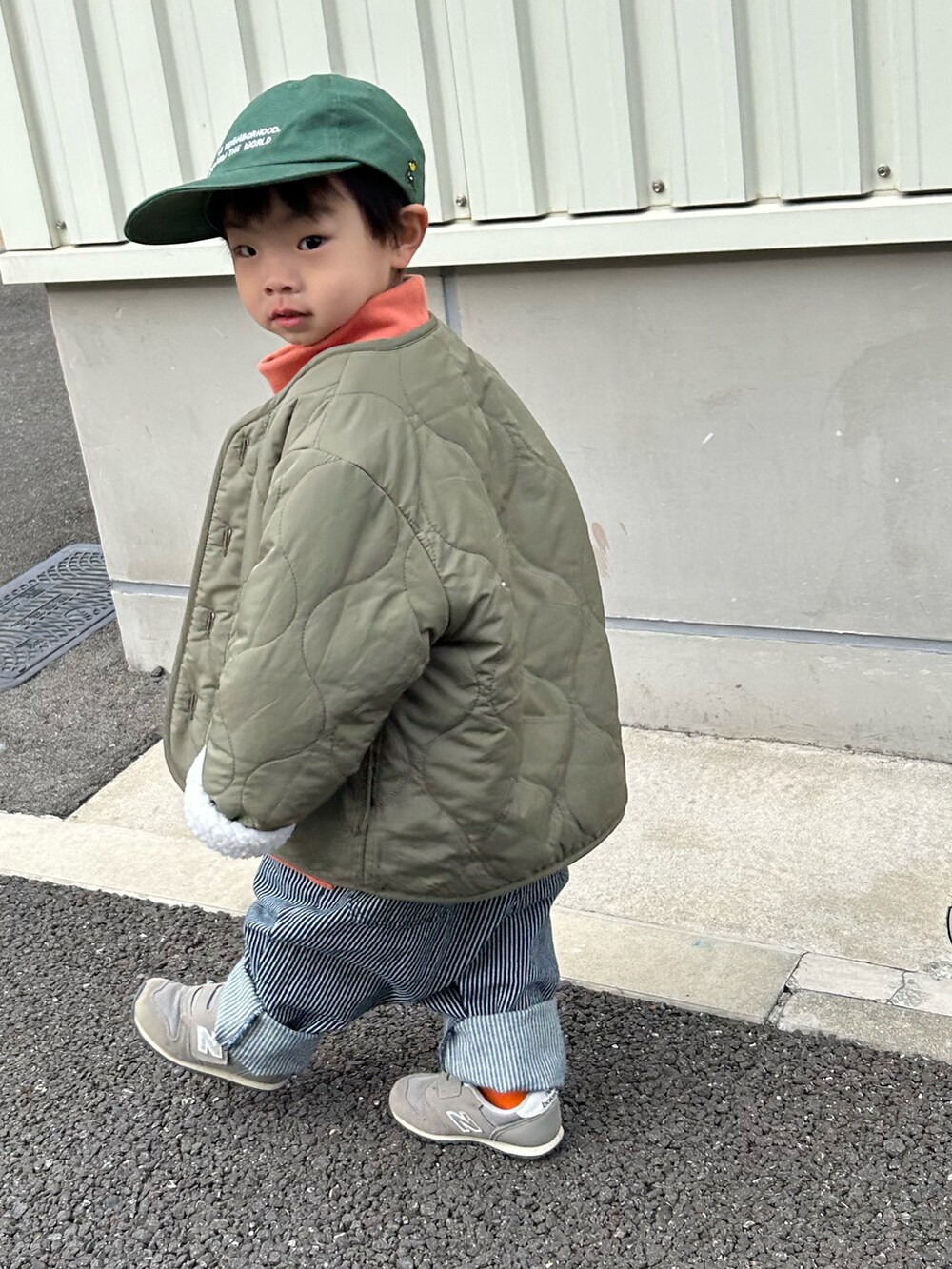 オレンジ系のスウェット、グリーン系のノーカラージャケット、ブルー系のデニムパンツを着用したキッズの冬コーディネートの4枚目の写真