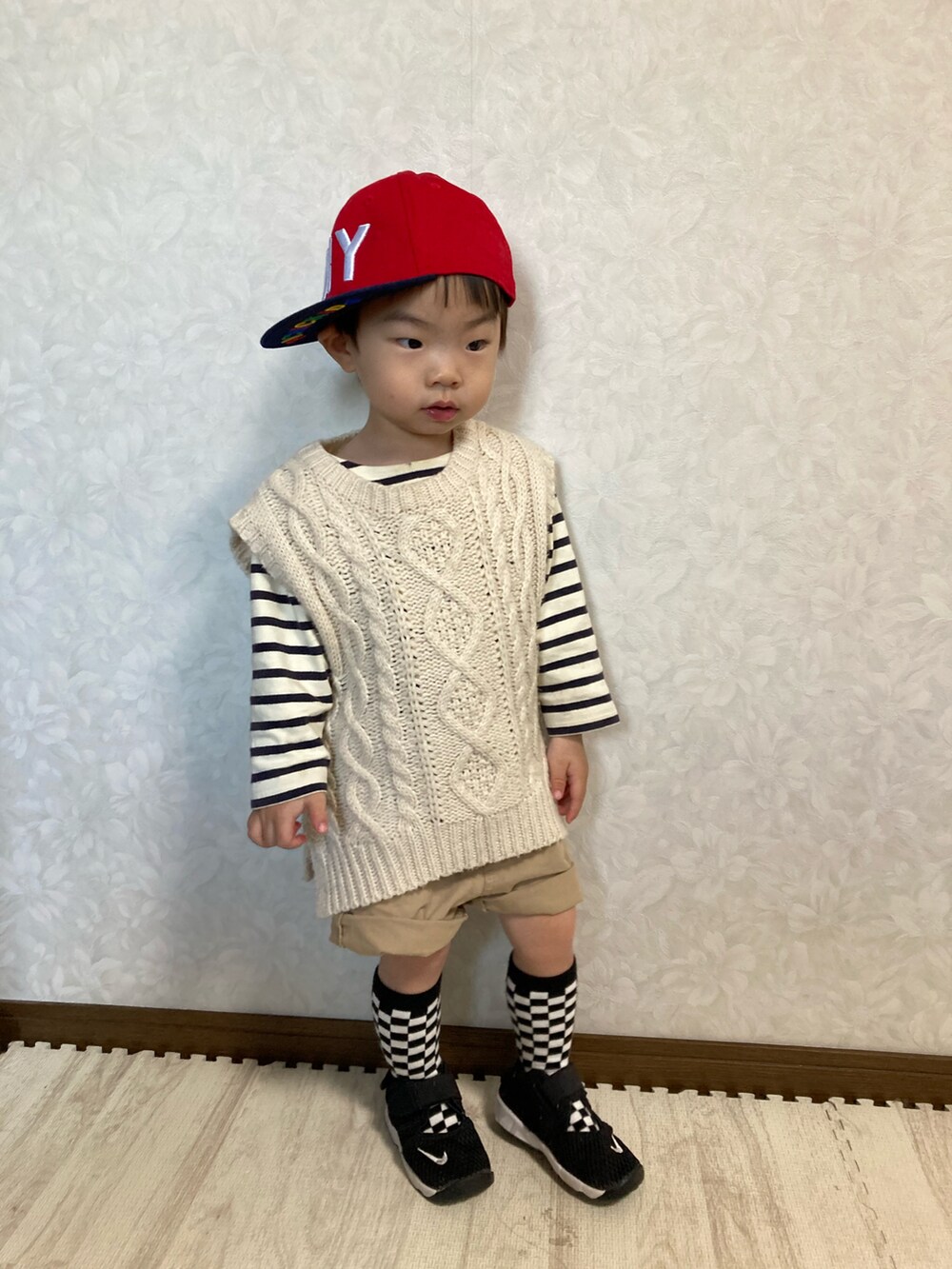 ホワイト系のベスト、ベージュ系のパンツ、ブラック系のスニーカーを着用したキッズの春コーディネートの4枚目の写真