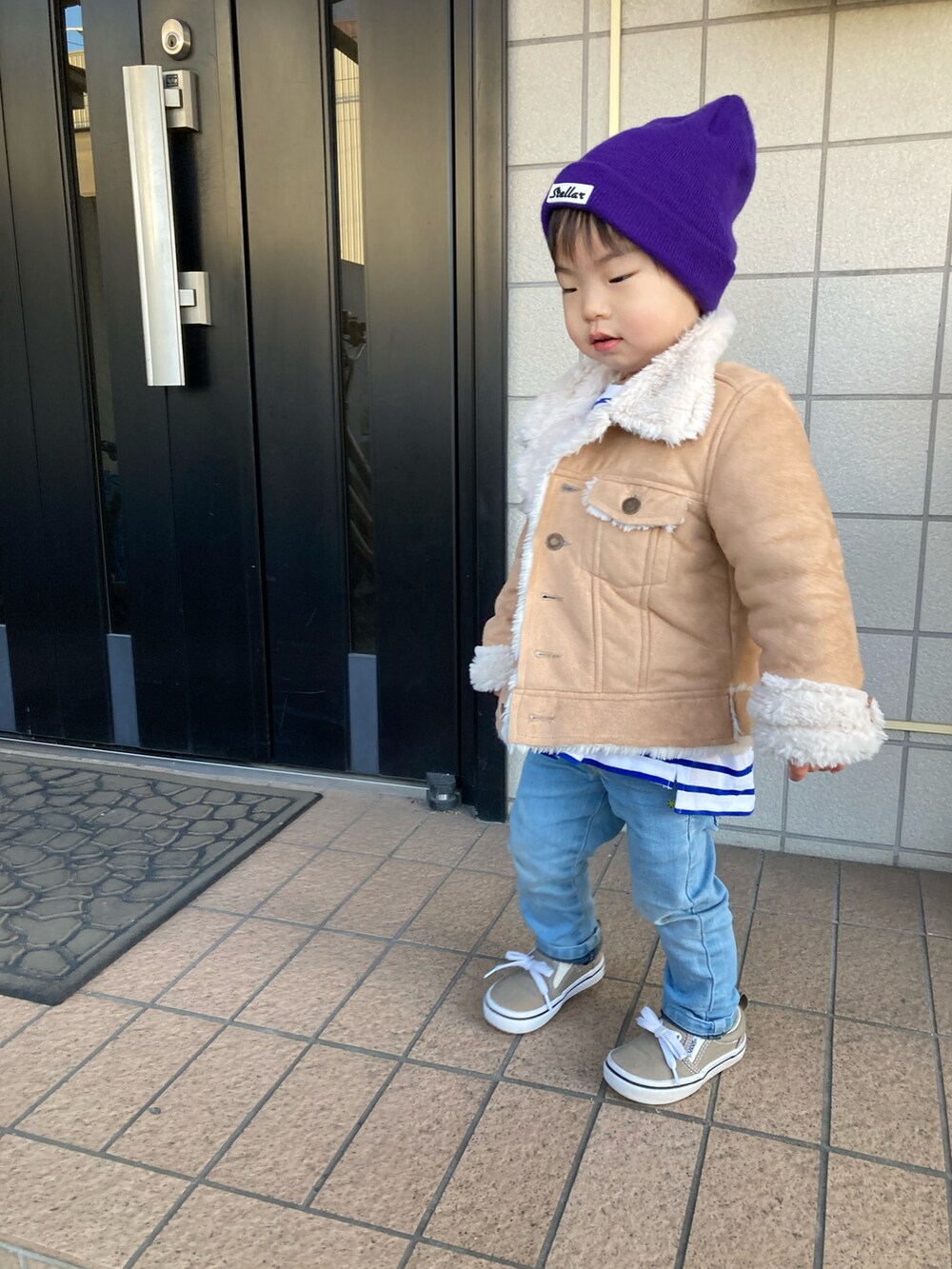 ベージュ系のジャケット/アウター、ブラウン系のスニーカー、ブルー系のキャップを着用したキッズの春コーディネートの3枚目の写真