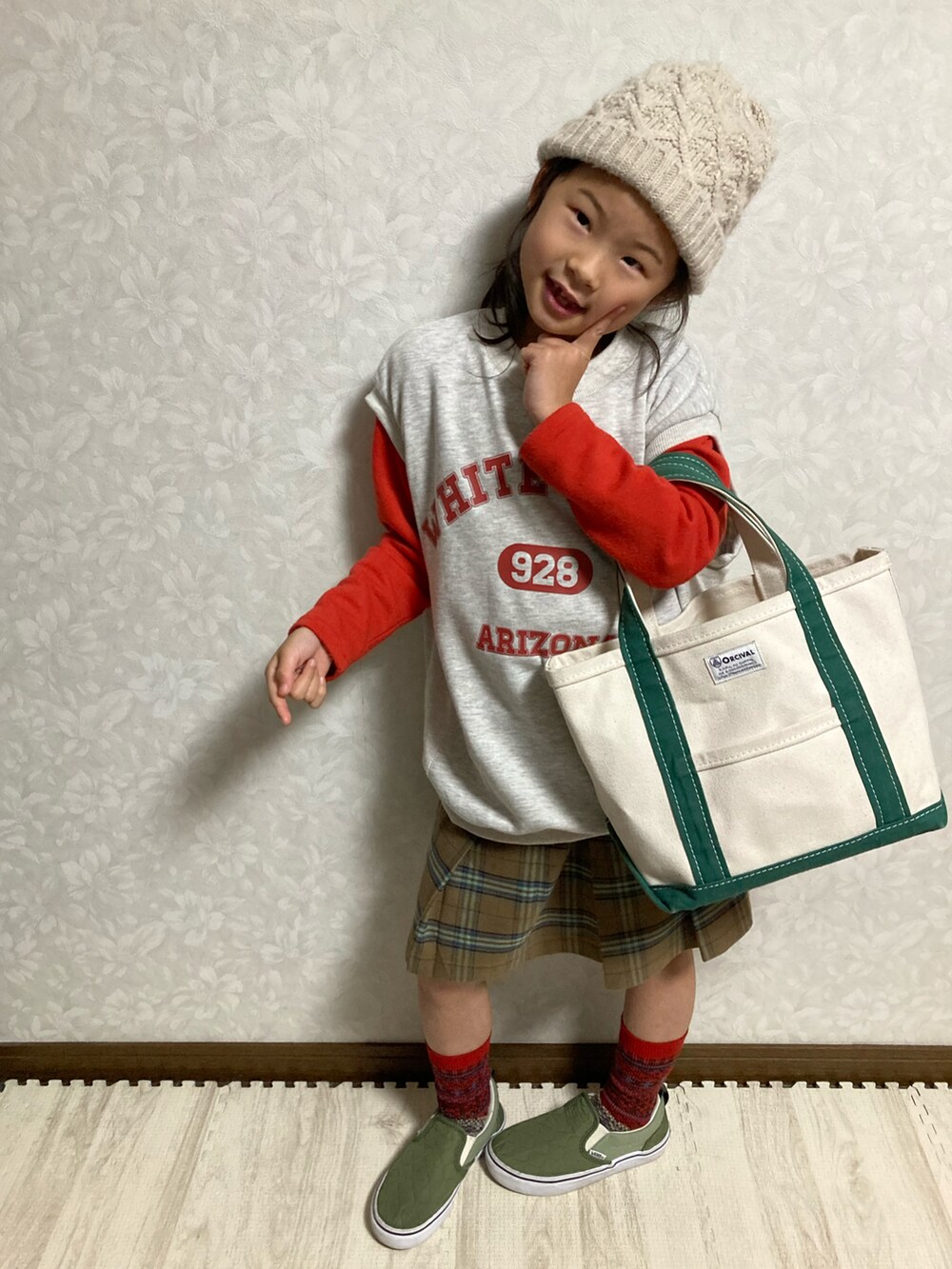 グレー系のベスト、ブラウン系のスカート、グリーン系のトートバッグを着用したキッズの冬コーディネートの4枚目の写真
