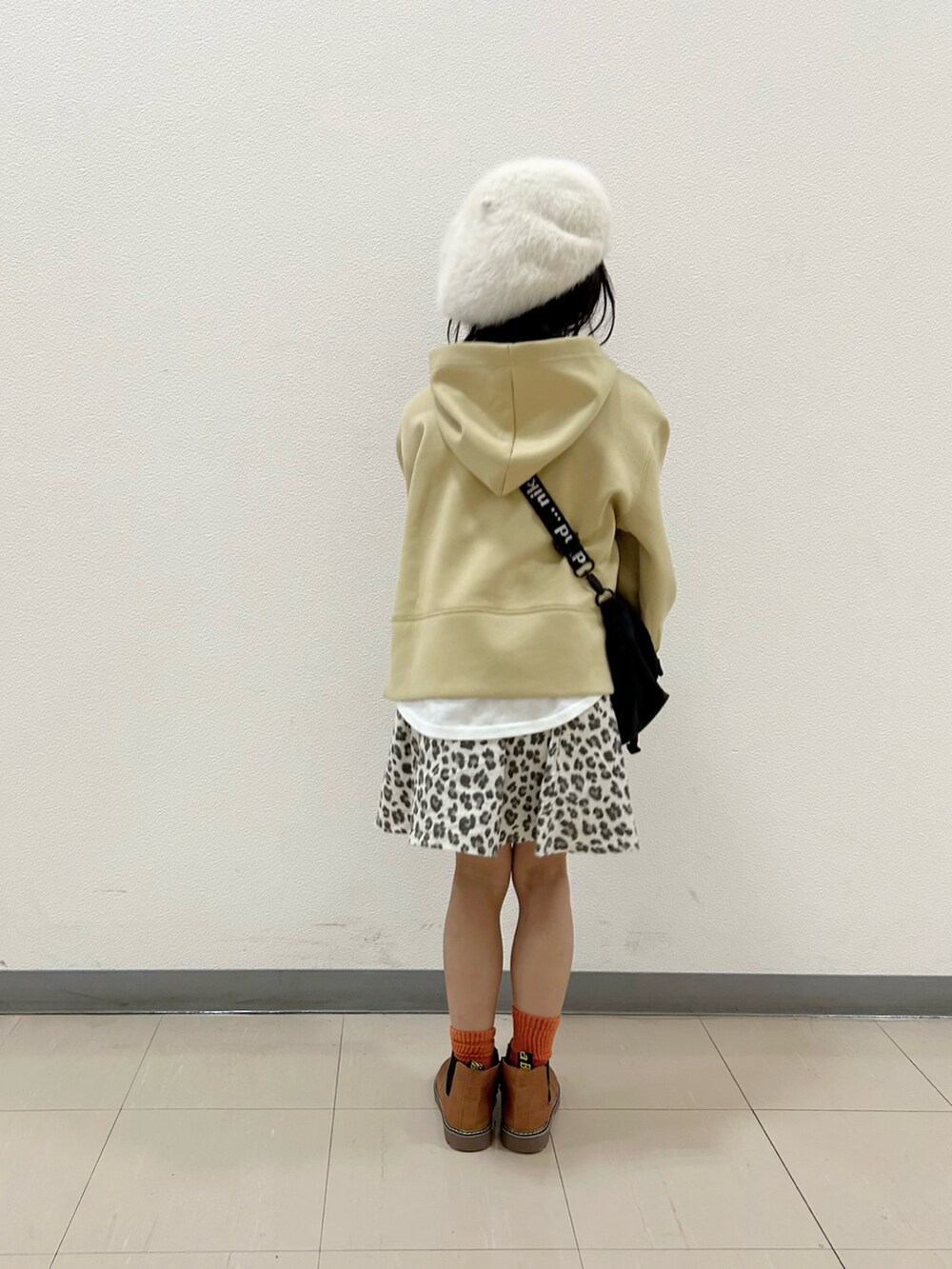 イエロー系のパーカー、ブラック系のショルダーバッグ、ベージュ系のスカートを着用したキッズの冬コーディネートの3枚目の写真