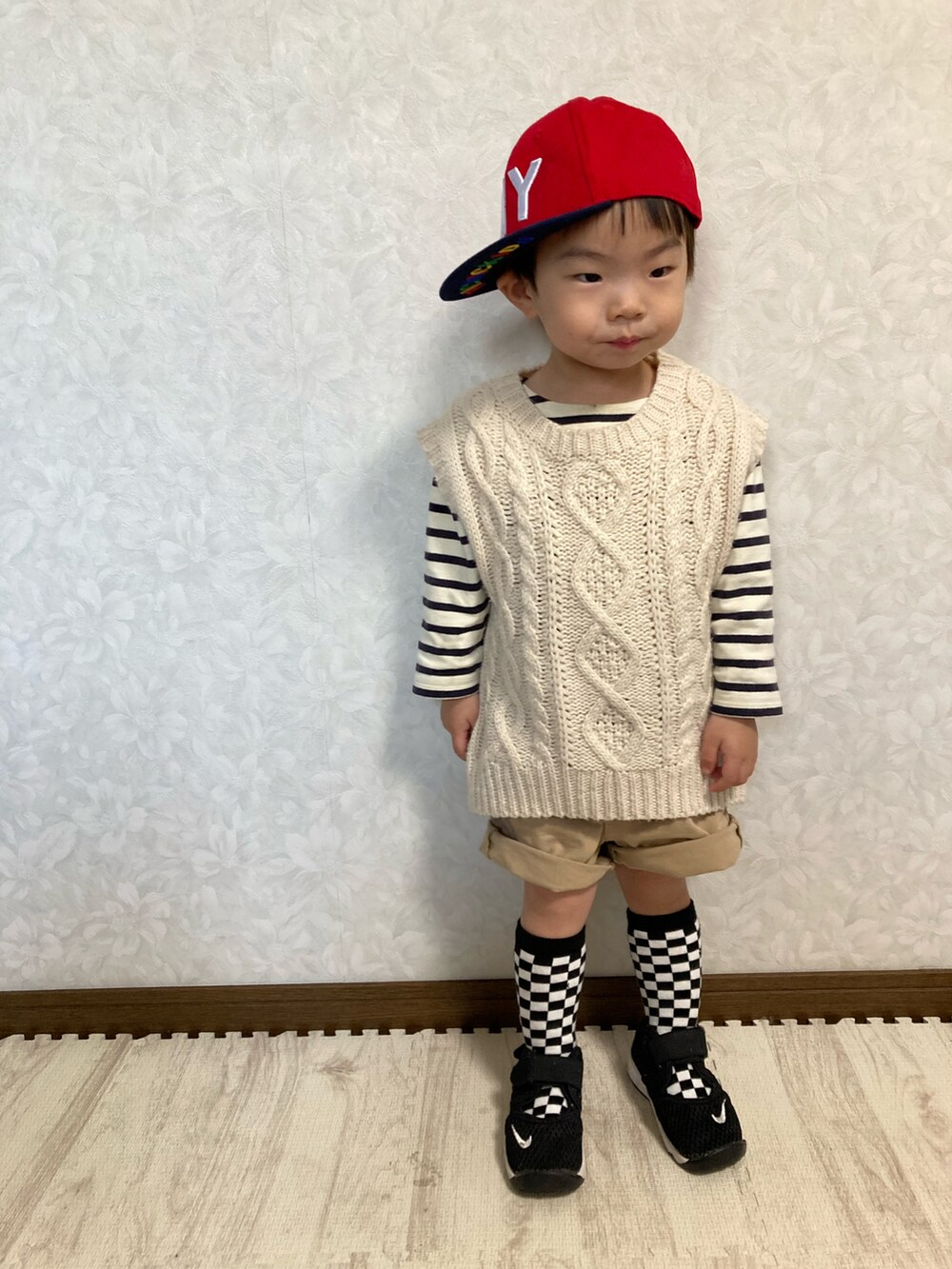 ホワイト系のベスト、ベージュ系のパンツ、ブラック系のスニーカーを着用したキッズの春コーディネートの5枚目の写真