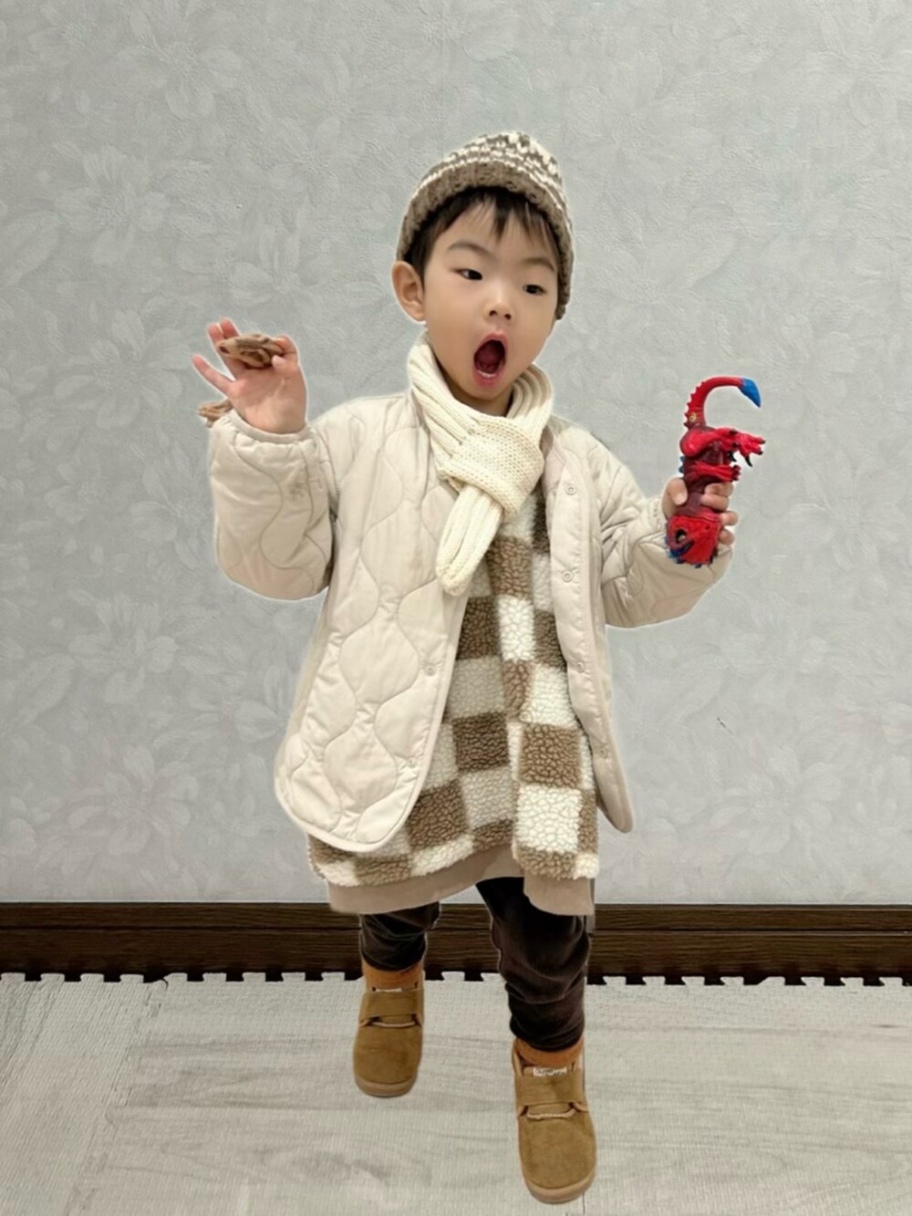 ブラウン系のベスト、ホワイト系のノーカラージャケット、ブラウン系のブーツを着用したキッズの冬コーディネートの2枚目の写真