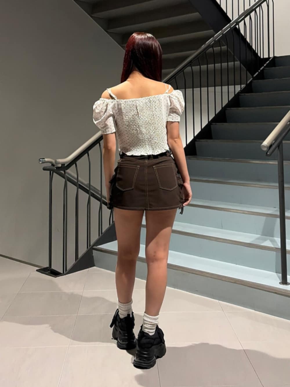 ブラック系のスニーカー、ブラウン系のスカート、ホワイト系のTシャツ/カットソーを着用したレディースの秋コーディネートの3枚目の写真