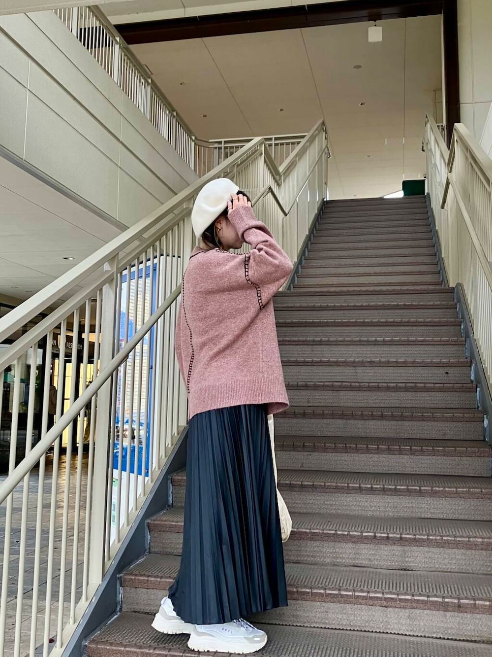 ピンク系のニット/セーター、ブラック系のスカート、ホワイト系のハンチング/ベレー帽を着用したレディースの冬コーディネートの3枚目の写真