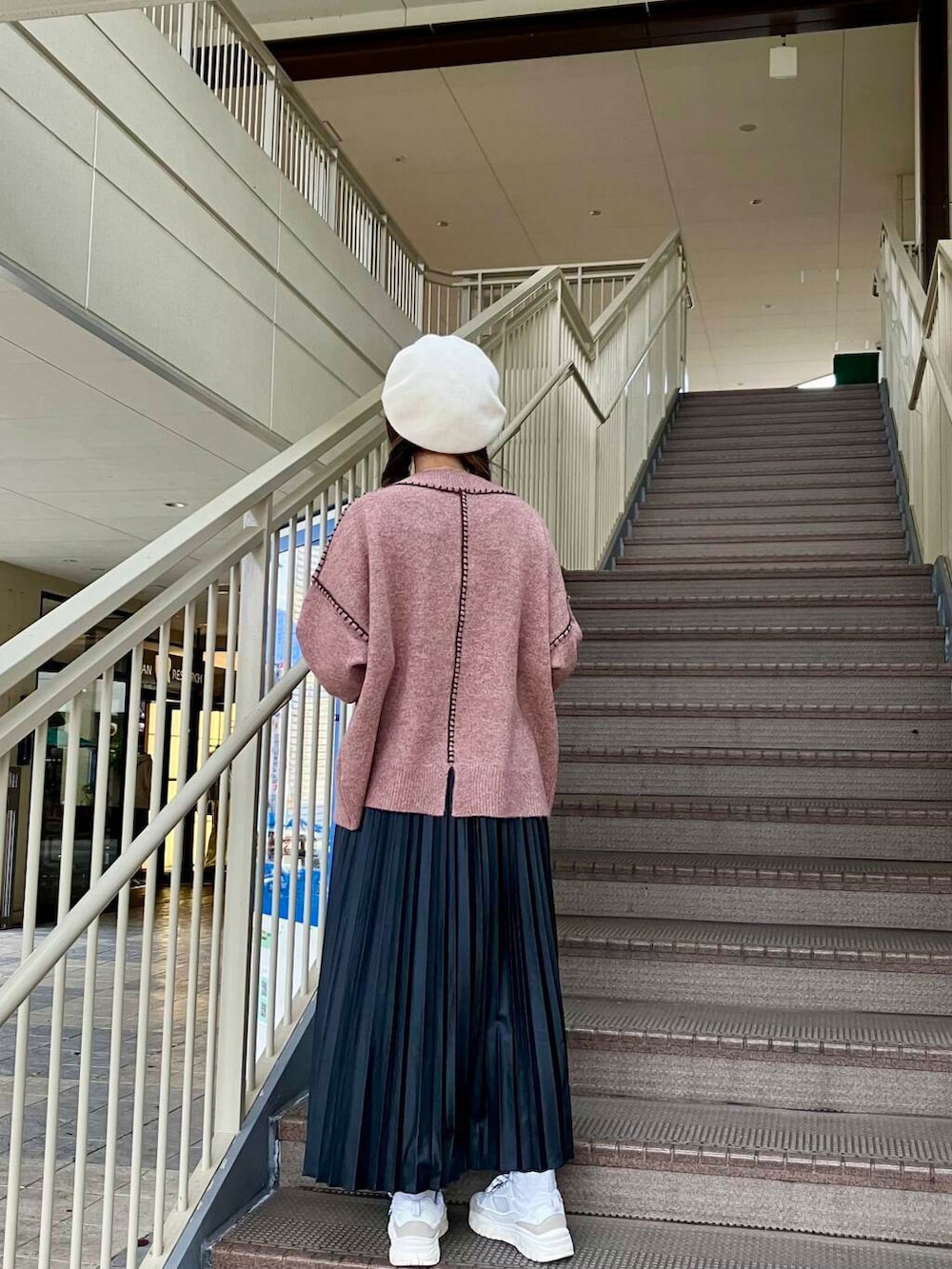 ピンク系のニット/セーター、ブラック系のスカート、ホワイト系のハンチング/ベレー帽を着用したレディースの冬コーディネートの2枚目の写真