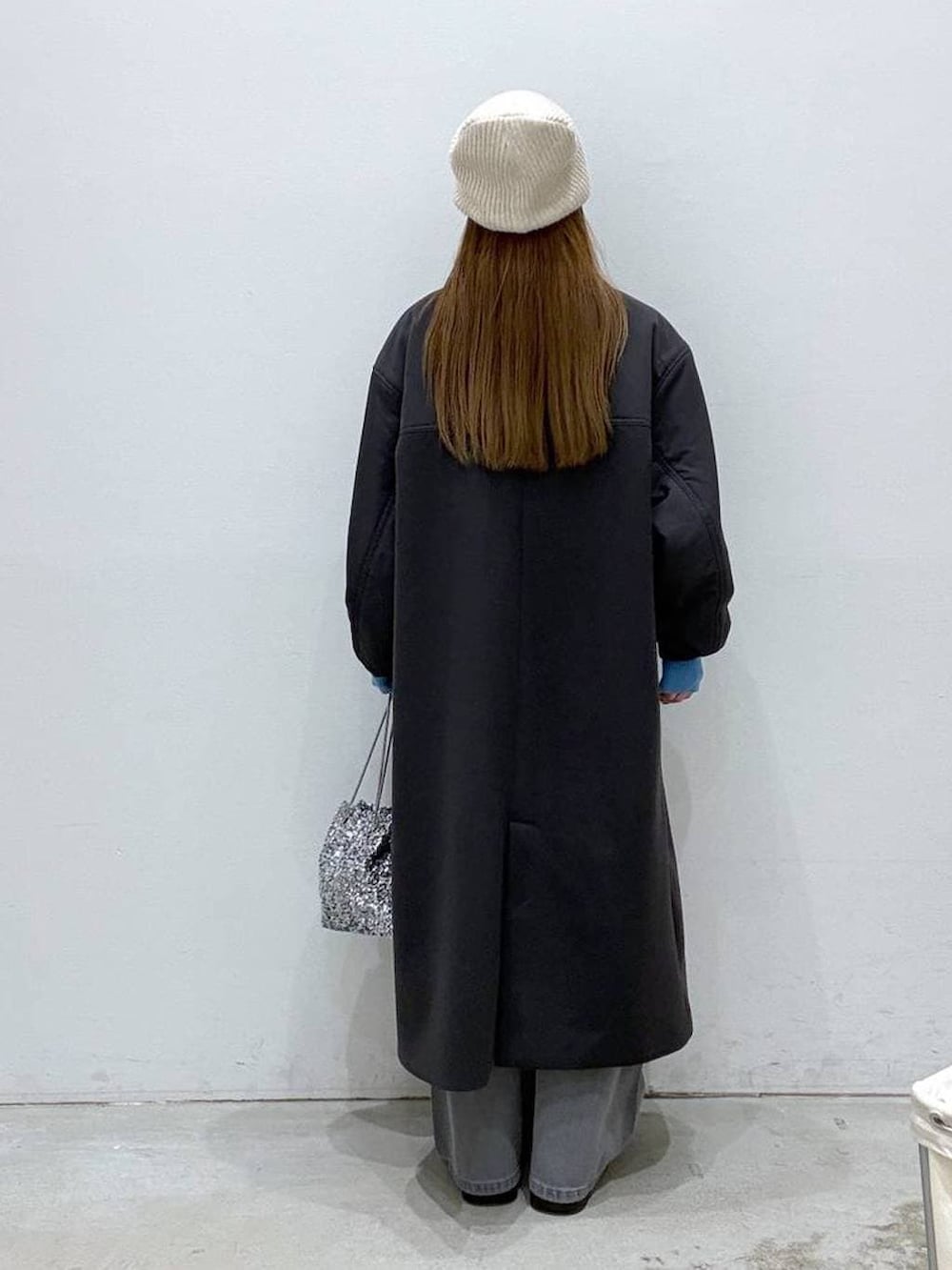 ブラウン系のニット/セーター、ブラック系のブーツ、シルバー系のショルダーバッグを着用したレディースの冬コーディネートの2枚目の写真