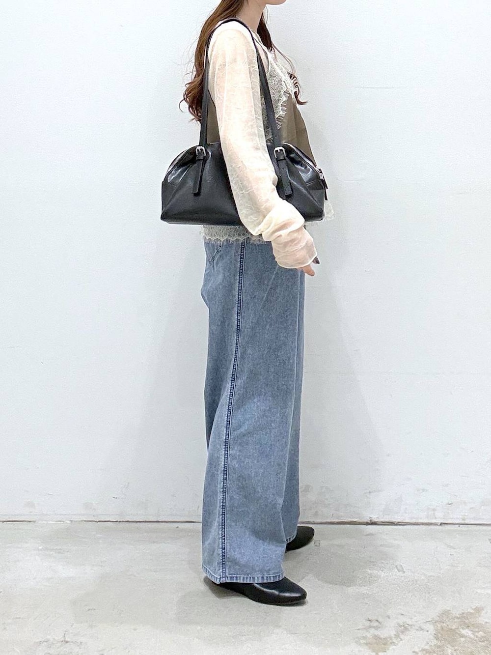 ブラック系のボストンバッグ、ブルー系のデニムパンツ、ブラック系のパンプスを着用したレディースの春コーディネートの2枚目の写真