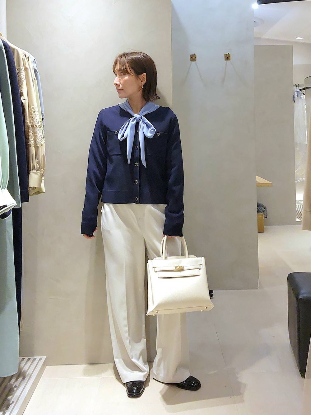 ホワイト系のトートバッグ、ブルー系のカーディガン/ボレロ、ベージュ系のスラックスを着用したレディースの冬コーディネートの4枚目の写真
