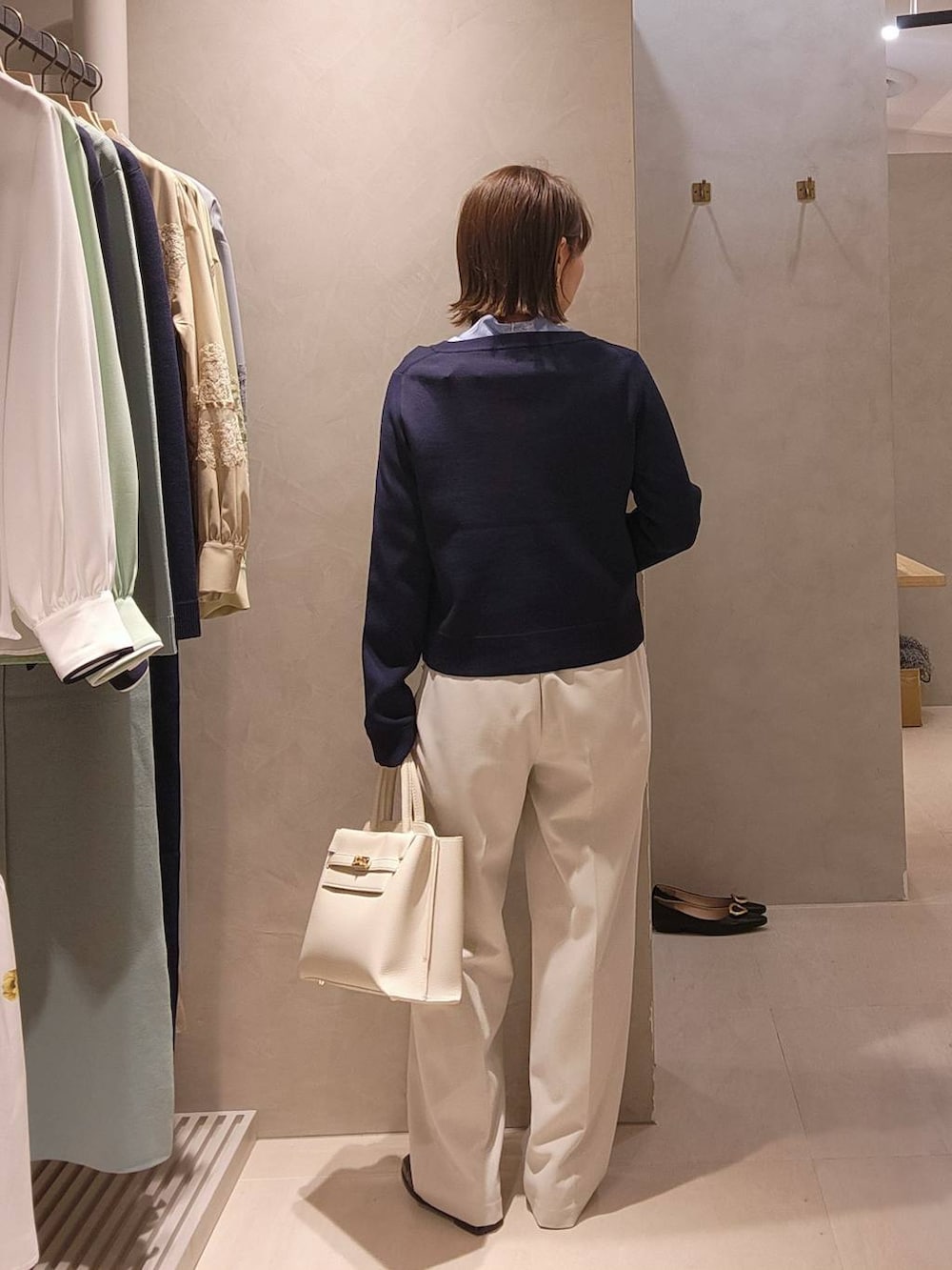 ホワイト系のトートバッグ、ブルー系のカーディガン/ボレロ、ベージュ系のスラックスを着用したレディースの冬コーディネートの3枚目の写真