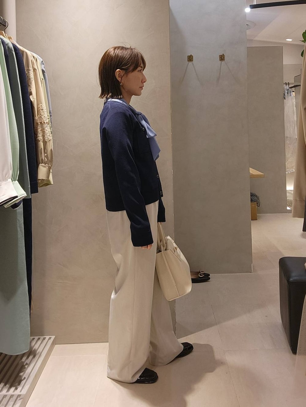 ホワイト系のトートバッグ、ブルー系のカーディガン/ボレロ、ベージュ系のスラックスを着用したレディースの冬コーディネートの2枚目の写真