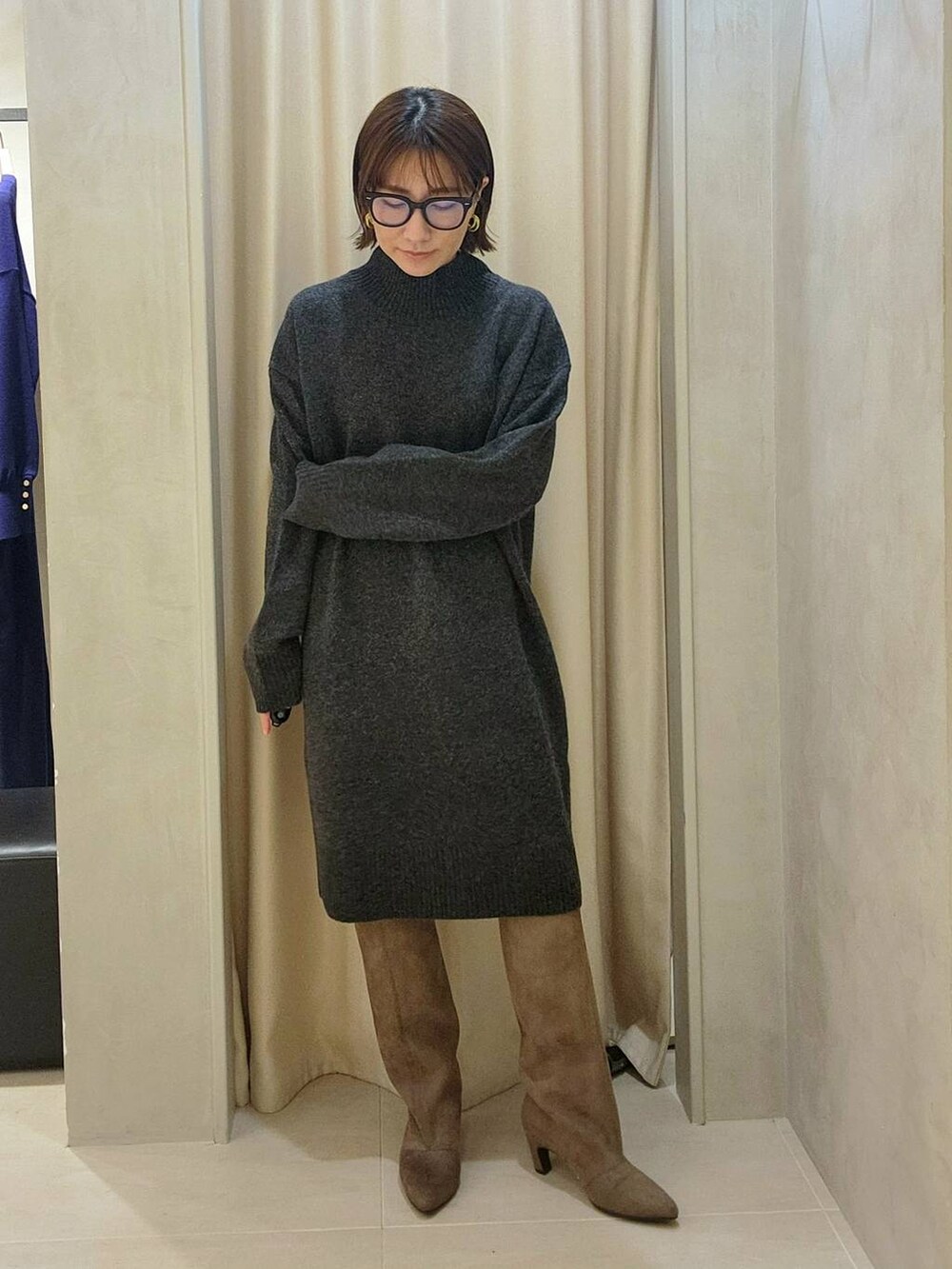 グレー系のチュニック、ベージュ系のブーツ、ブラック系のメガネを着用したレディースの秋コーディネートの2枚目の写真