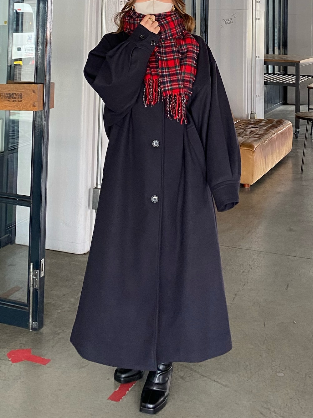 ブラック系のバッグ、ブラック系のステンカラーコート、ブラック系のブーツを着用したレディースの冬コーディネートの2枚目の写真