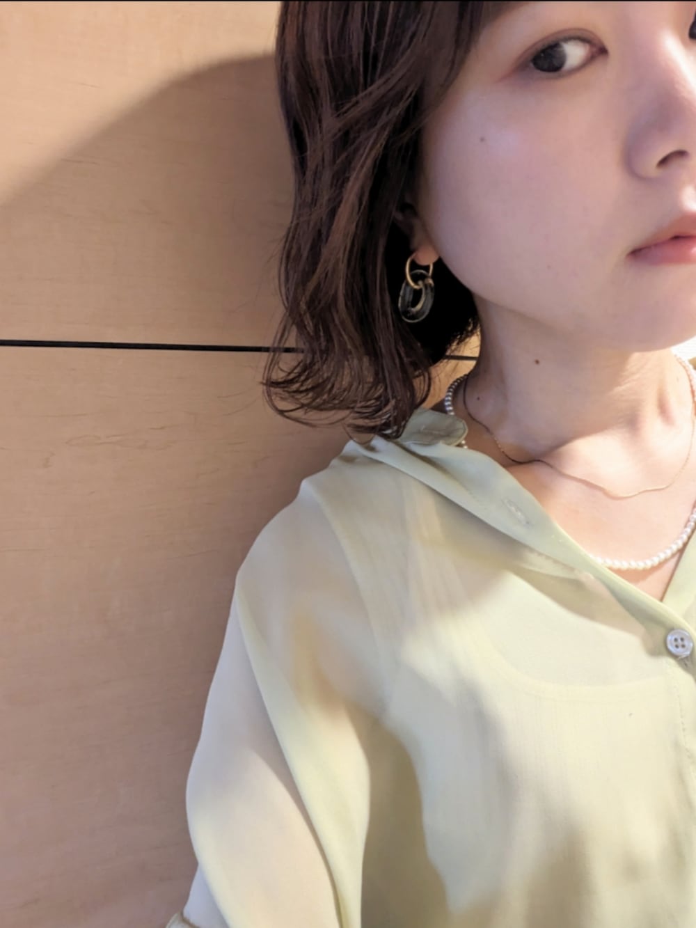 グリーン系のシャツ/ブラウス、グレー系のスラックスを着用したレディースの夏コーディネートの3枚目の写真