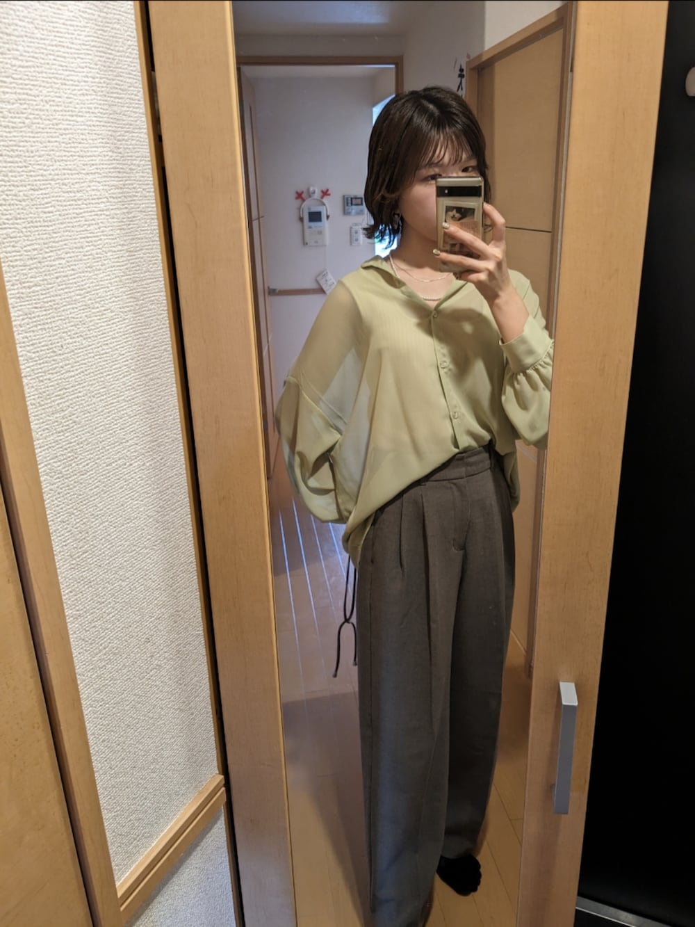 グリーン系のシャツ/ブラウス、グレー系のスラックスを着用したレディースの夏コーディネートの2枚目の写真