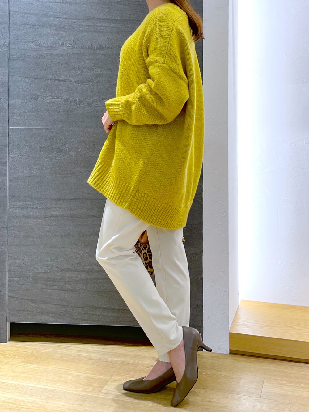 イエロー系のニット/セーター、ホワイト系のその他パンツ、その他のショルダーバッグを着用したレディースの冬コーディネートの2枚目の写真