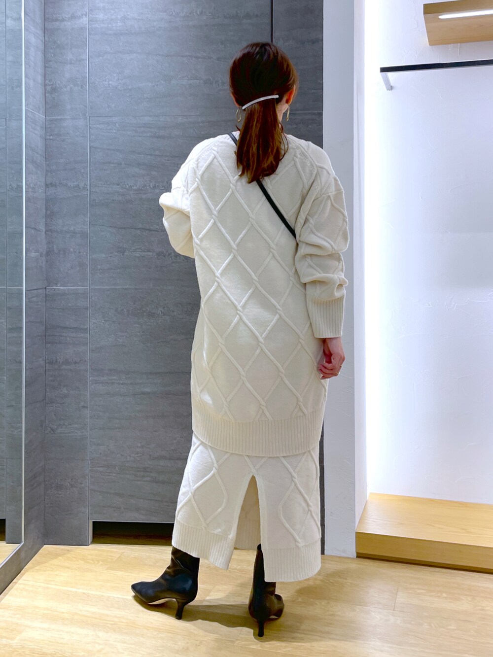 ホワイト系のニット/セーター、ホワイト系のスカート、ブラック系のブーツを着用したレディースの冬コーディネートの3枚目の写真