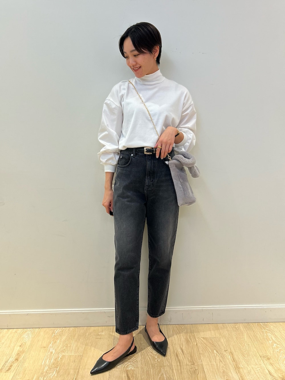 グレー系のトートバッグ、ブラック系のデニムパンツ、ブラック系のベルトを着用したレディースの冬コーディネートの3枚目の写真