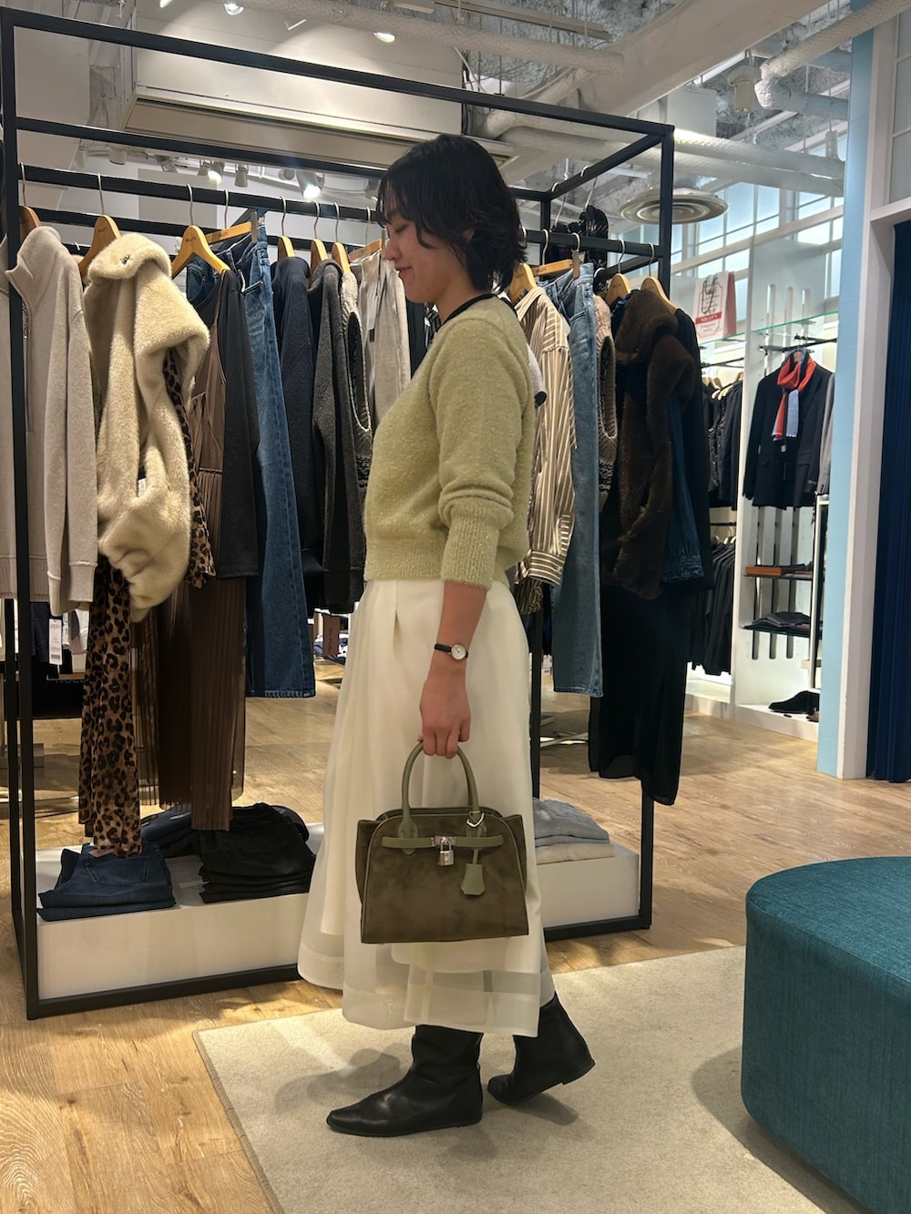 ホワイト系のスカート、イエロー系のニット/セーター、グリーン系のトートバッグを着用したレディースの冬コーディネートの4枚目の写真