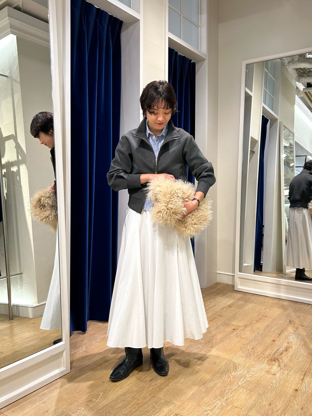 グレー系のブルゾン、ブルー系のシャツ/ブラウス、ホワイト系のスカートを着用したレディースの秋コーディネートの2枚目の写真