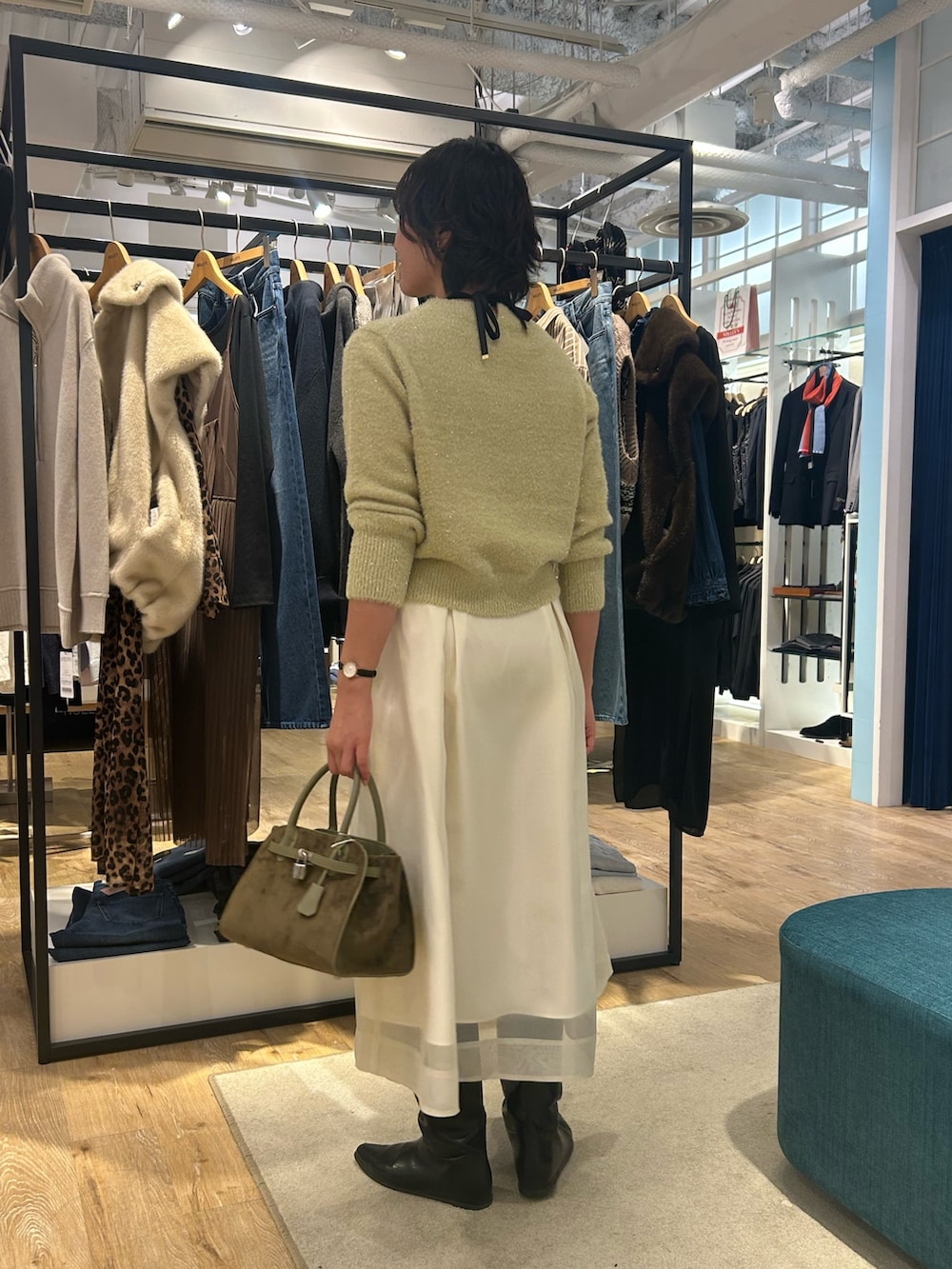 ホワイト系のスカート、イエロー系のニット/セーター、グリーン系のトートバッグを着用したレディースの冬コーディネートの5枚目の写真