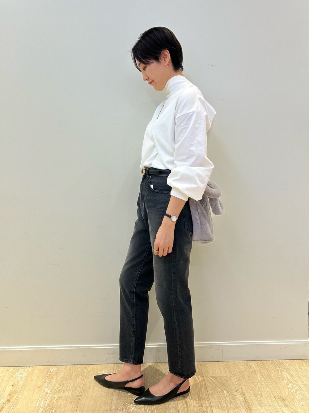 グレー系のトートバッグ、ブラック系のデニムパンツ、ブラック系のベルトを着用したレディースの冬コーディネートの4枚目の写真