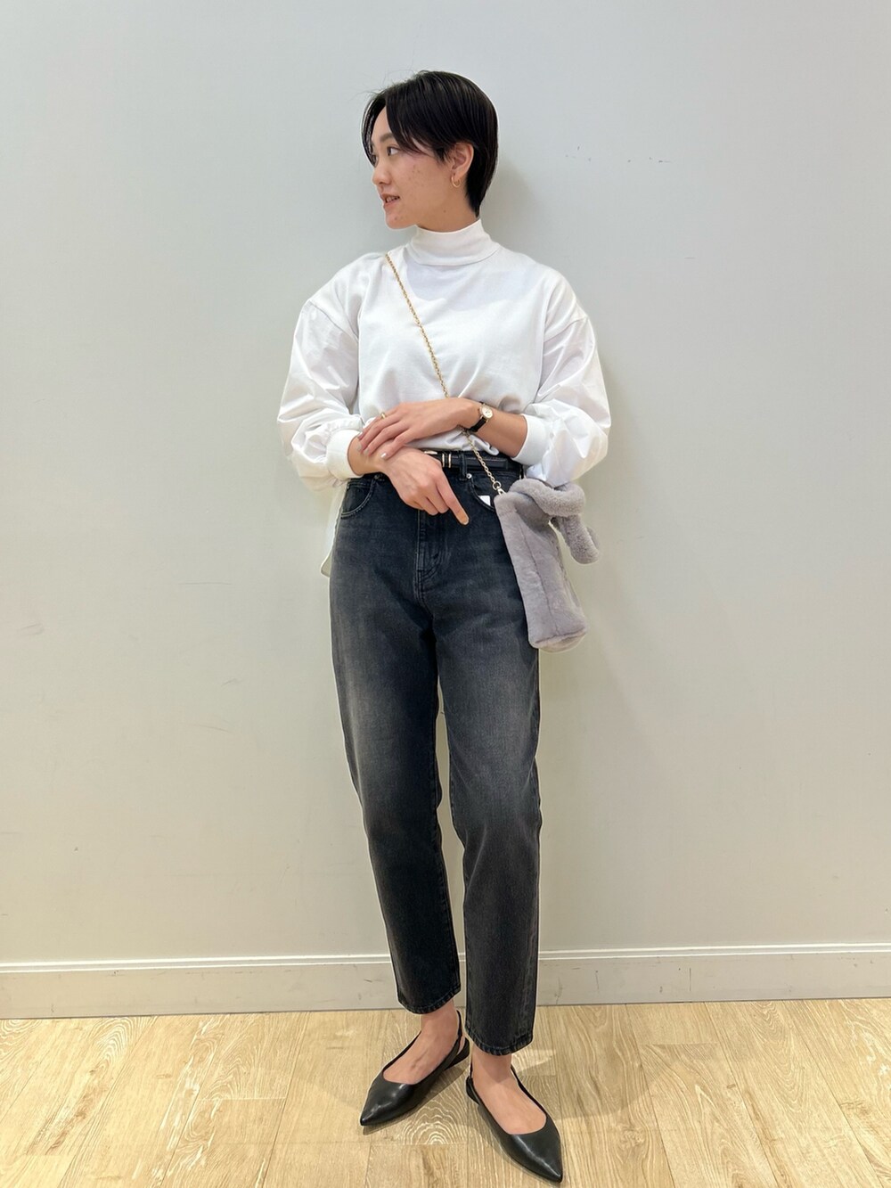 グレー系のトートバッグ、ブラック系のデニムパンツ、ブラック系のベルトを着用したレディースの冬コーディネートの2枚目の写真