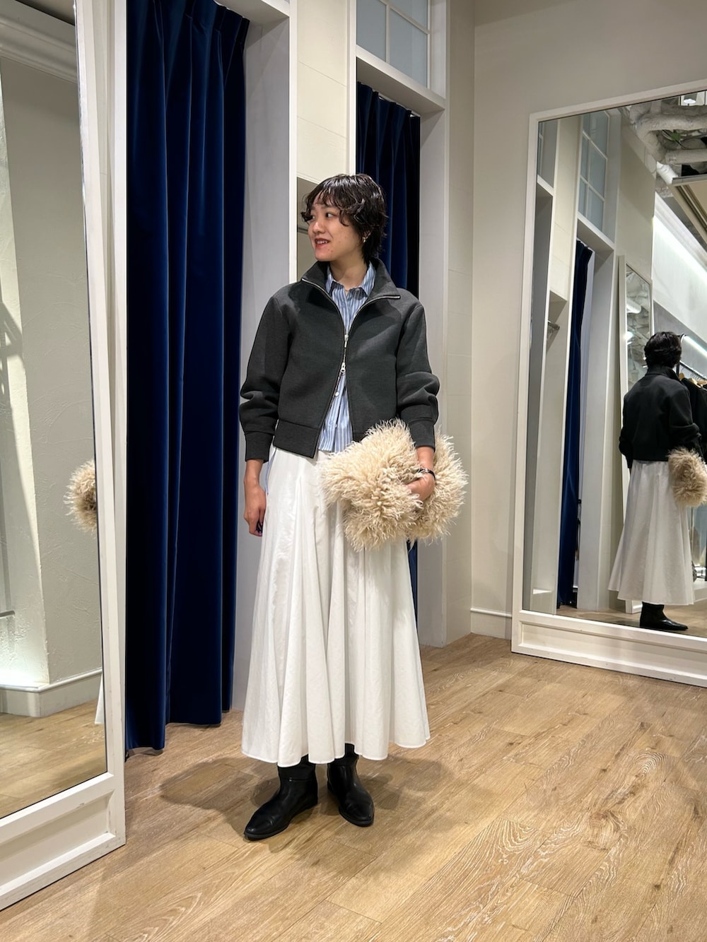 グレー系のブルゾン、ブルー系のシャツ/ブラウス、ホワイト系のスカートを着用したレディースの秋コーディネートの3枚目の写真