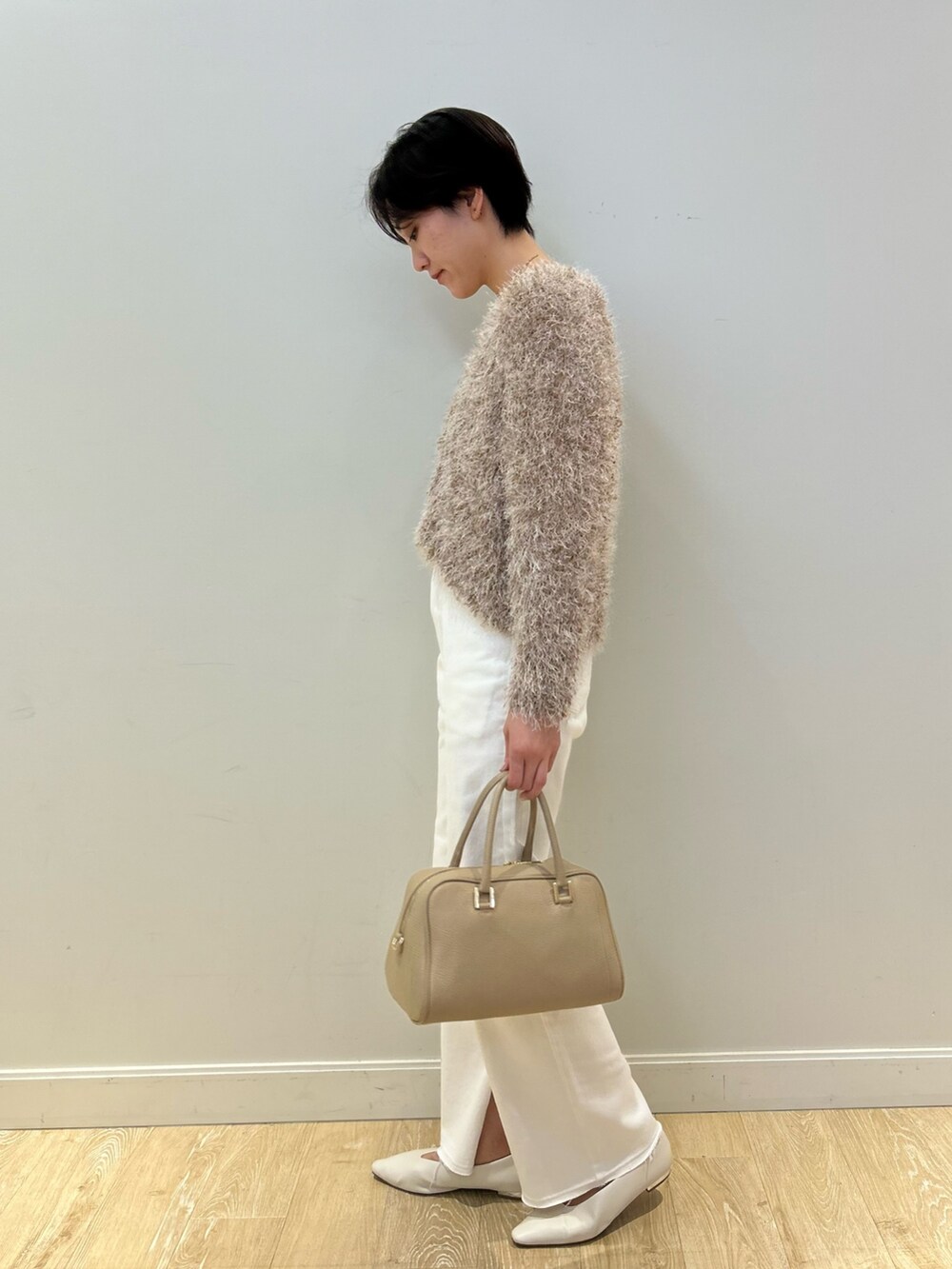 ホワイト系のタンクトップ、ベージュ系のカーディガン/ボレロ、ホワイト系のデニムパンツを着用したレディースの冬コーディネートの4枚目の写真