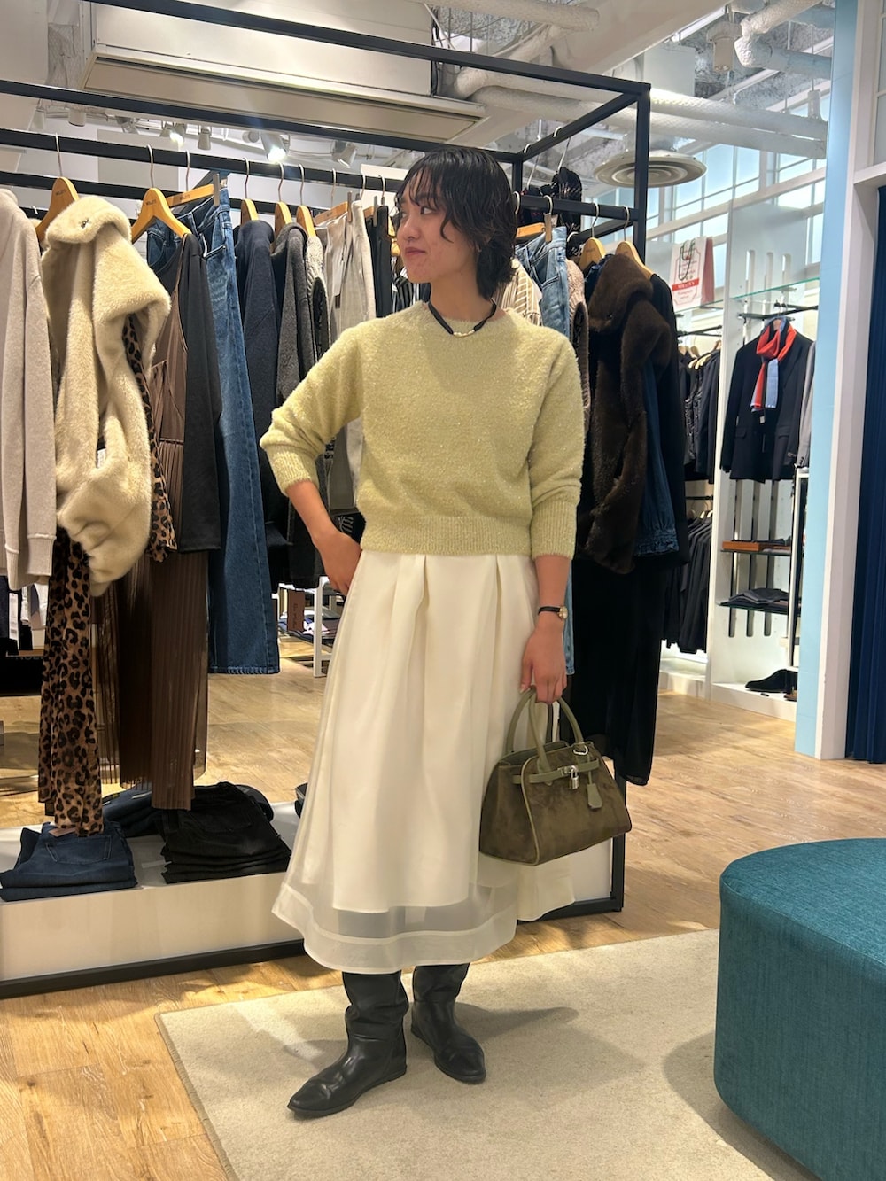 ホワイト系のスカート、イエロー系のニット/セーター、グリーン系のトートバッグを着用したレディースの冬コーディネートの3枚目の写真